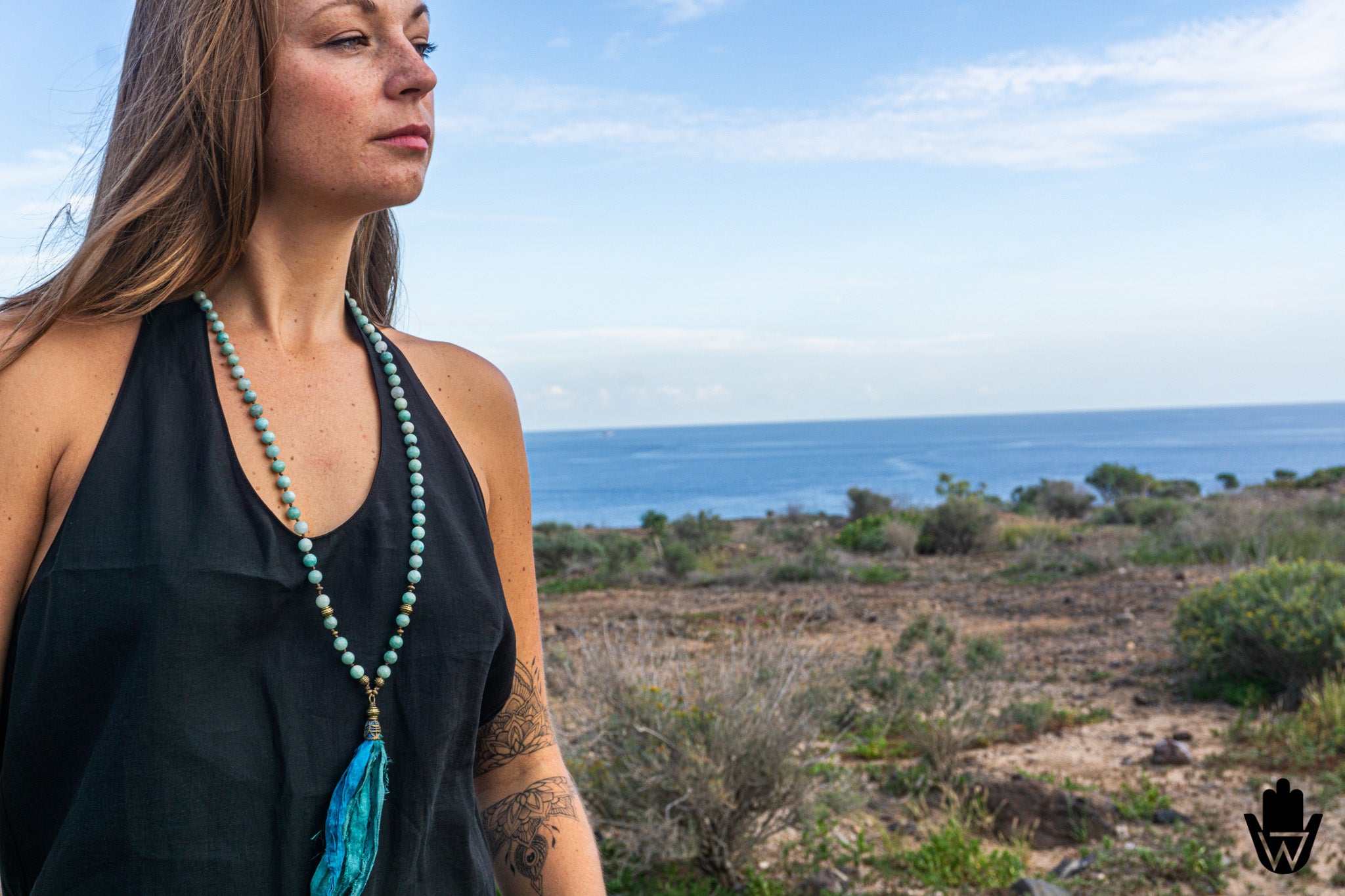 woman in front of the ocean wearing a lonh mala necklace
