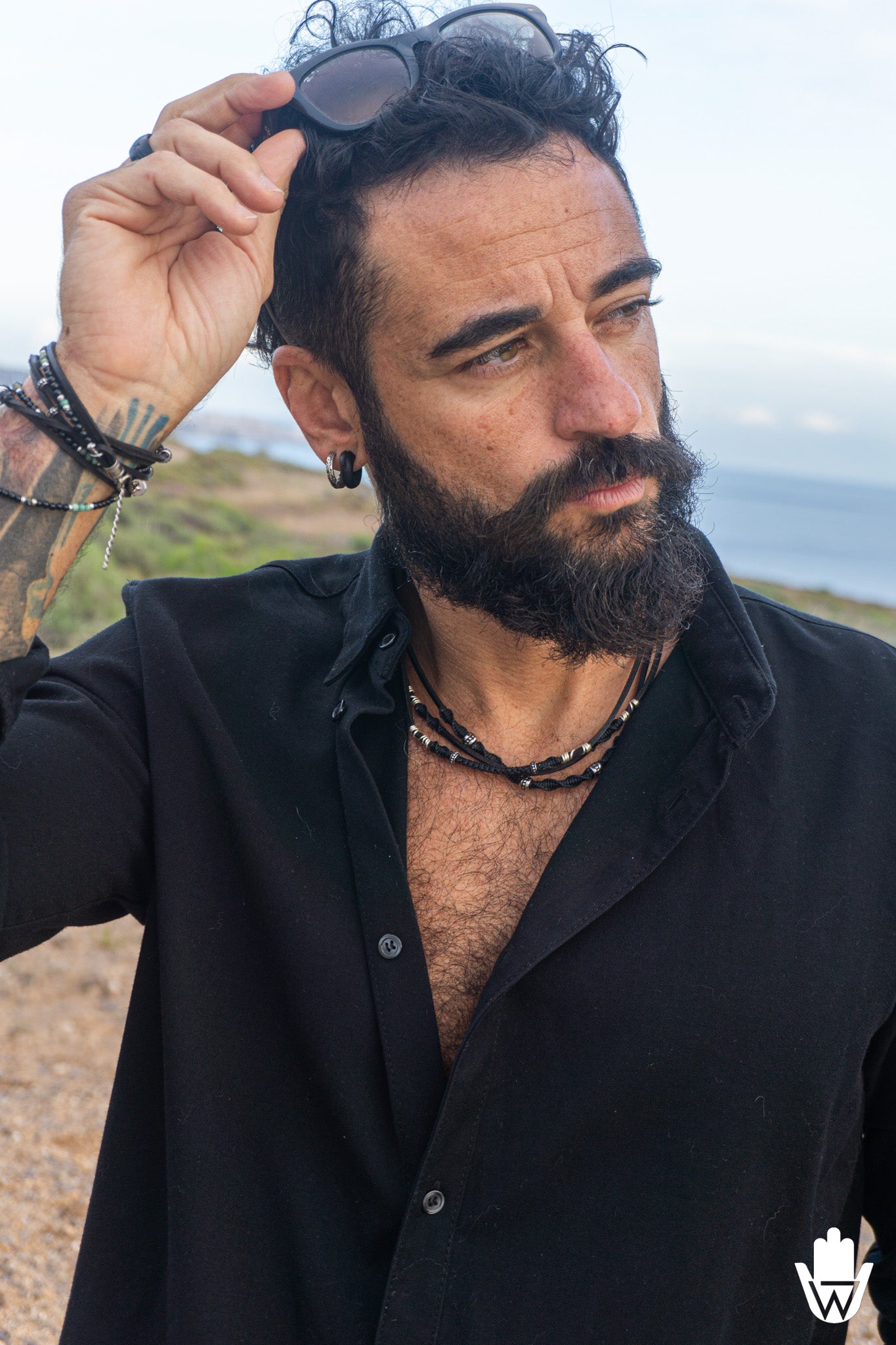 mens with black sirt waering black sunglasses and a multistrand necklace