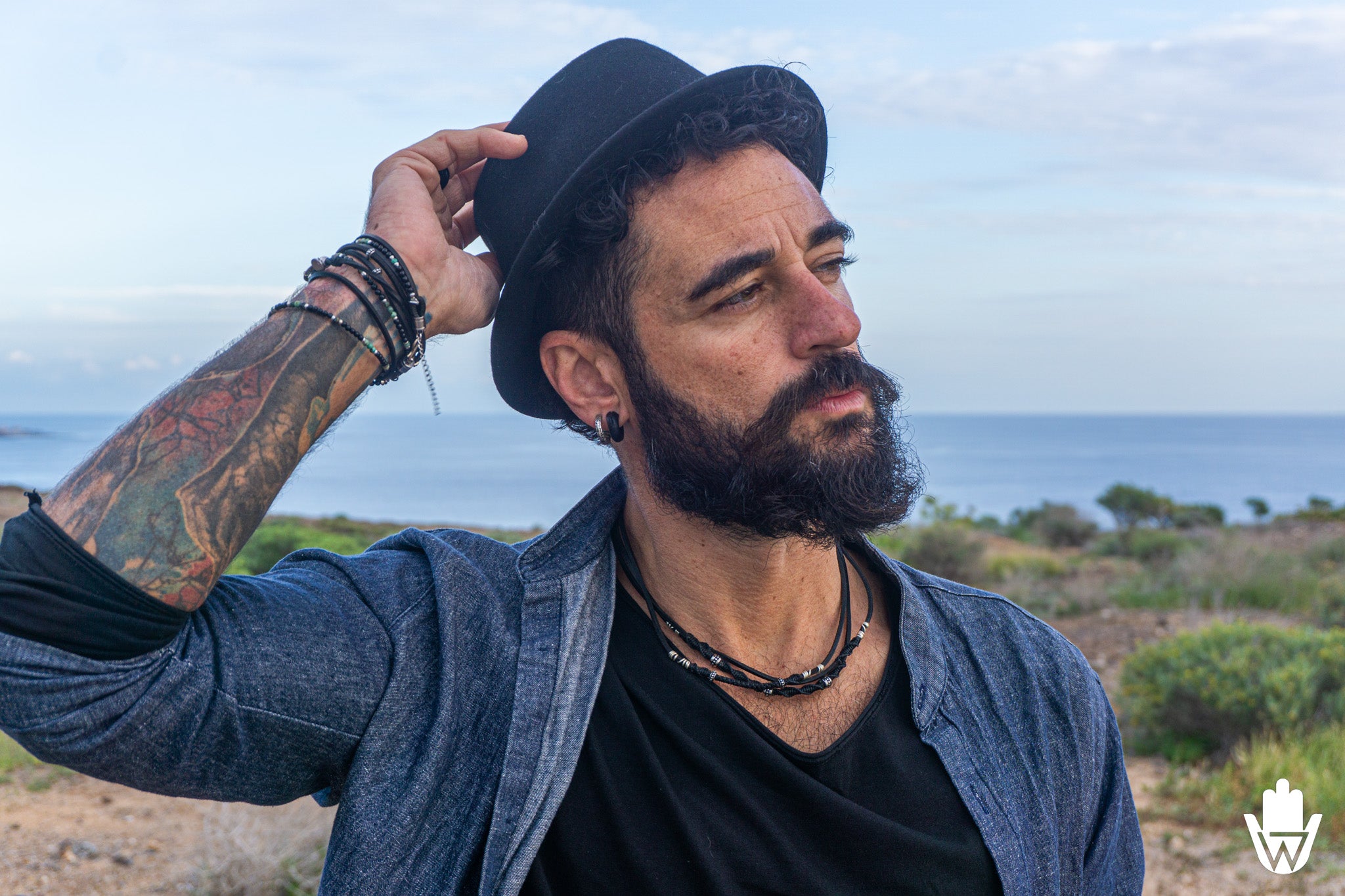 man with hat and boho layering ewelry