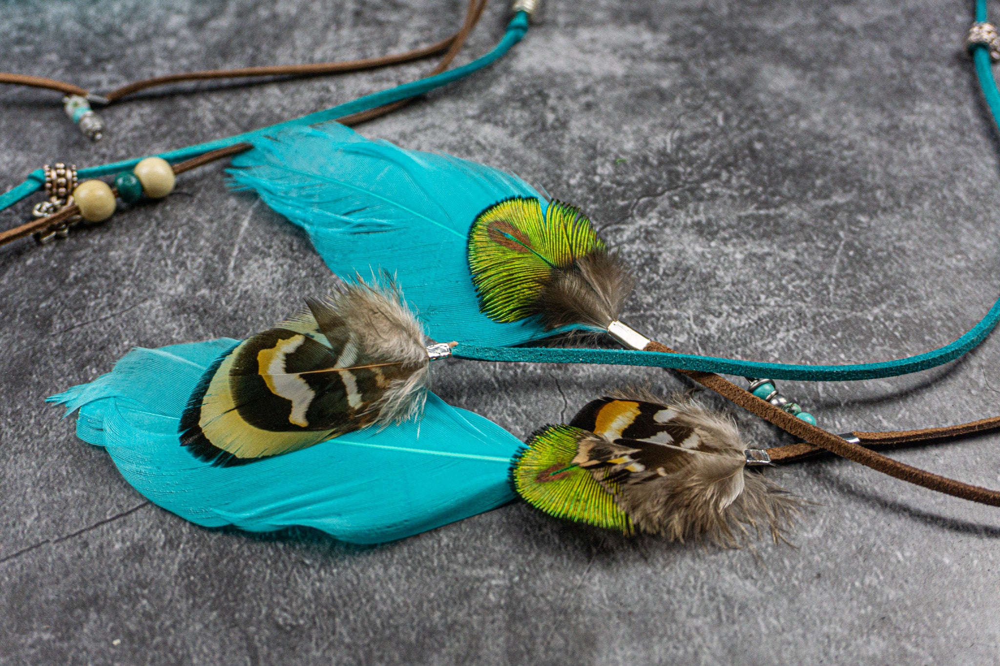 Feathered jewelry pieces on a textured surface