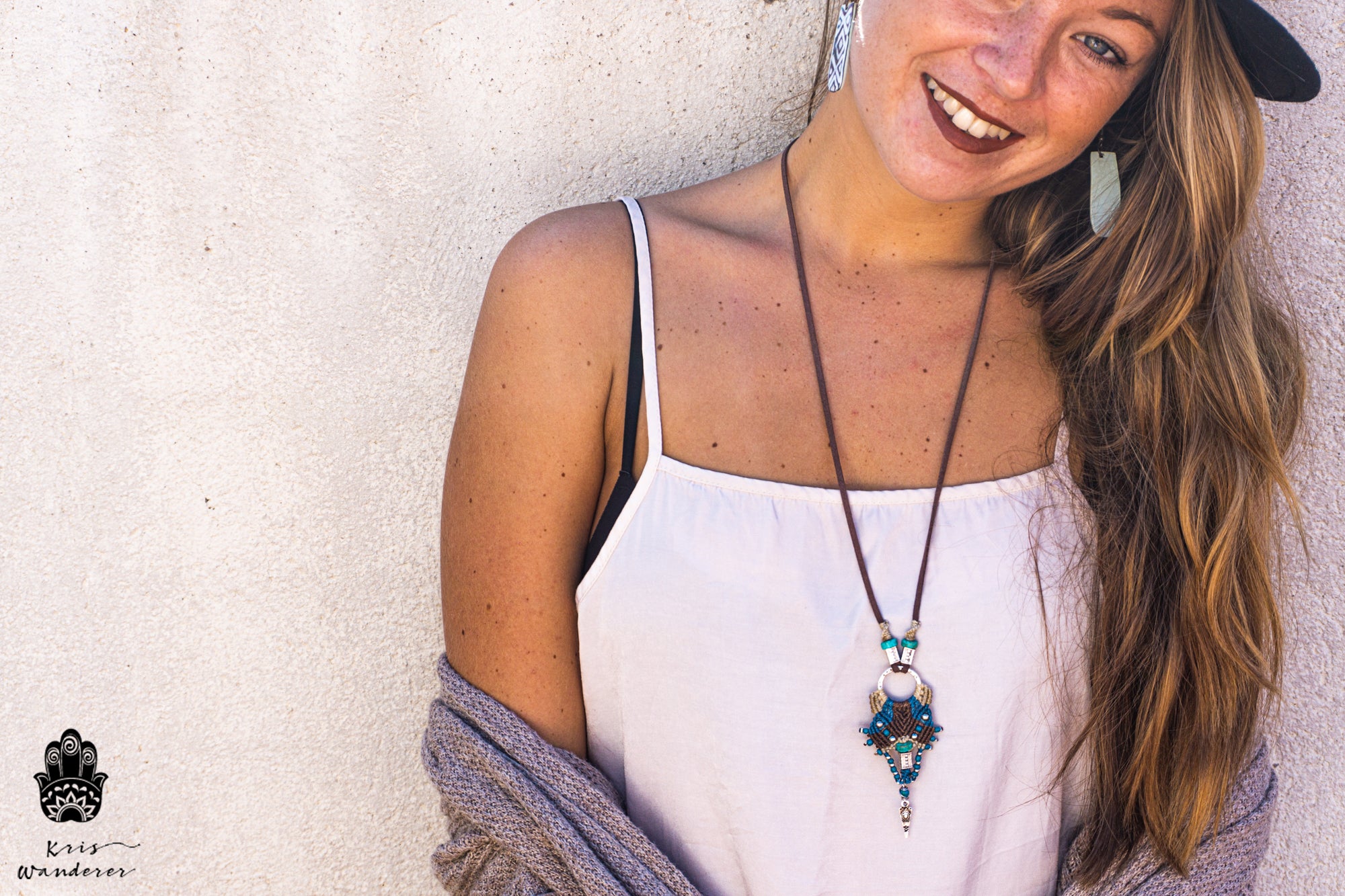Woman wearing a long necklace with a decorative pendant against a neutral background- wander jewellery