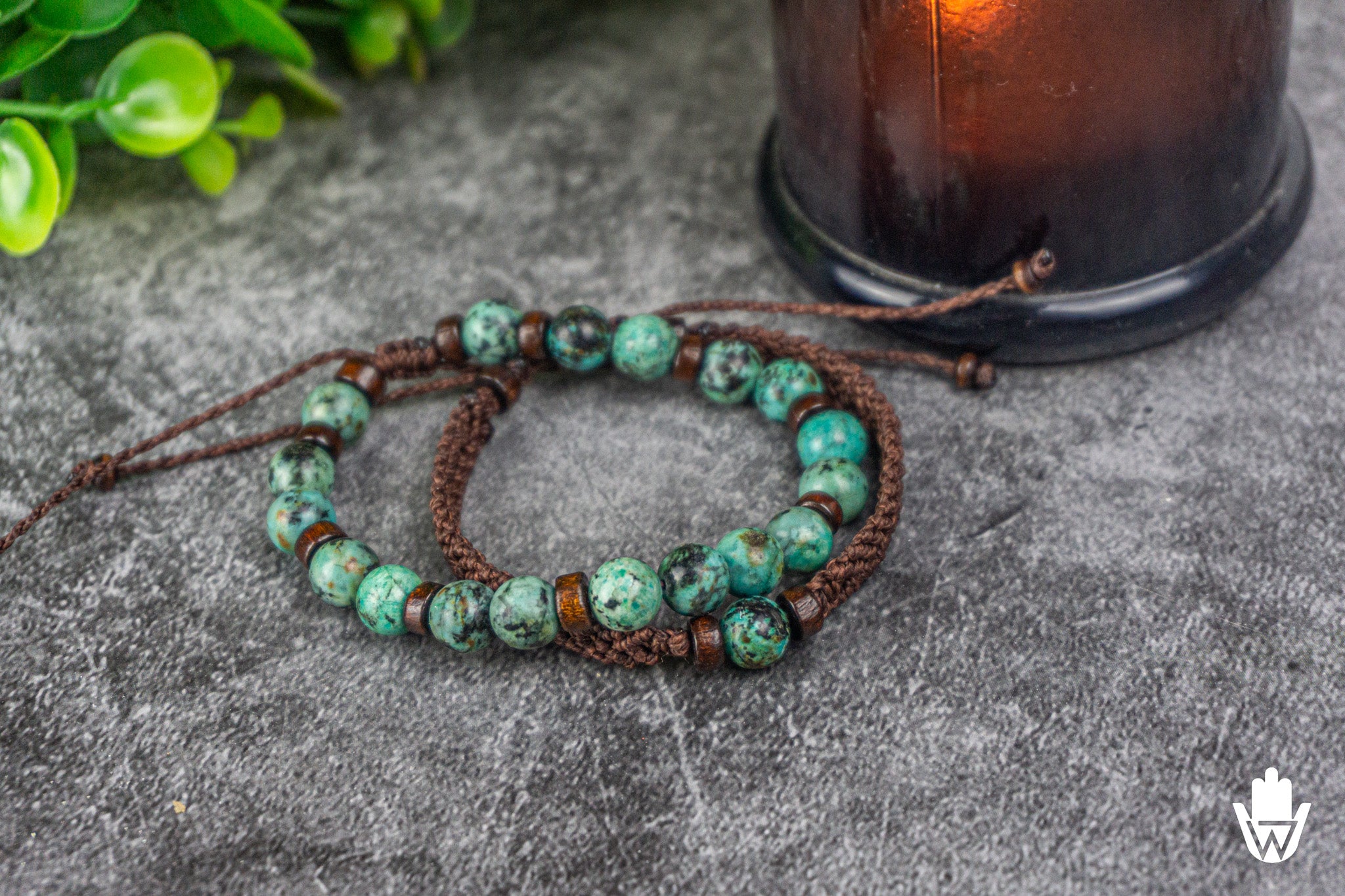 Beaded bracelet set with green beads on a textured surface with a plant in the background
