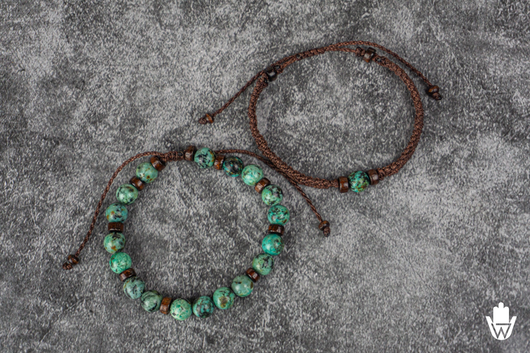 Two matching beaded bracelets on a textured gray surface