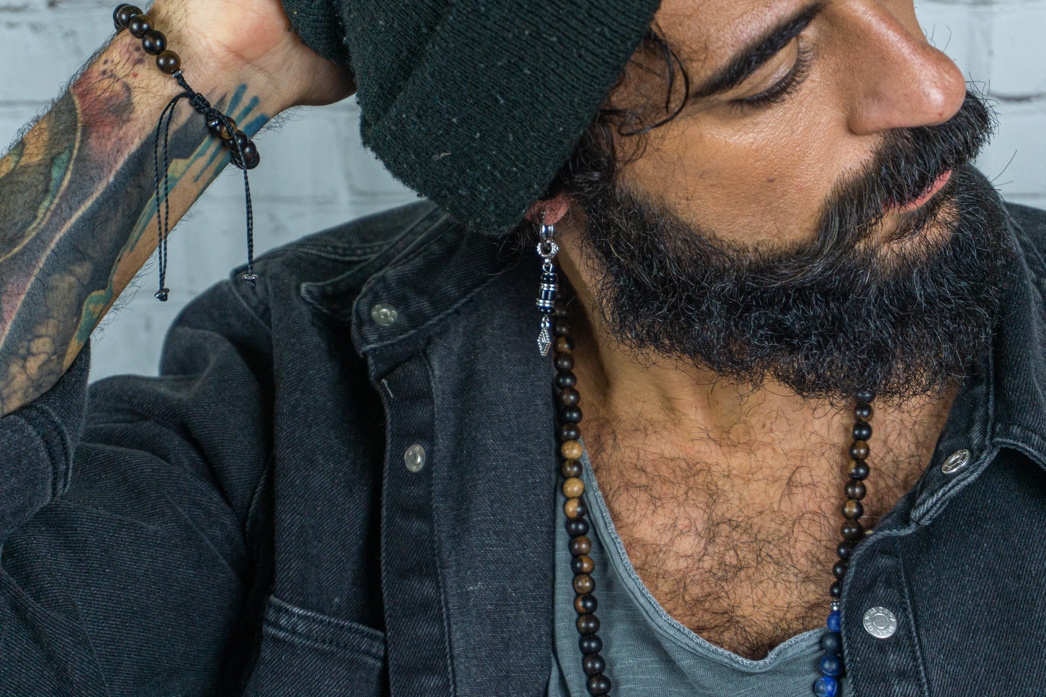 Man with black jeans jacket and black beanie with a silver dangling earring
