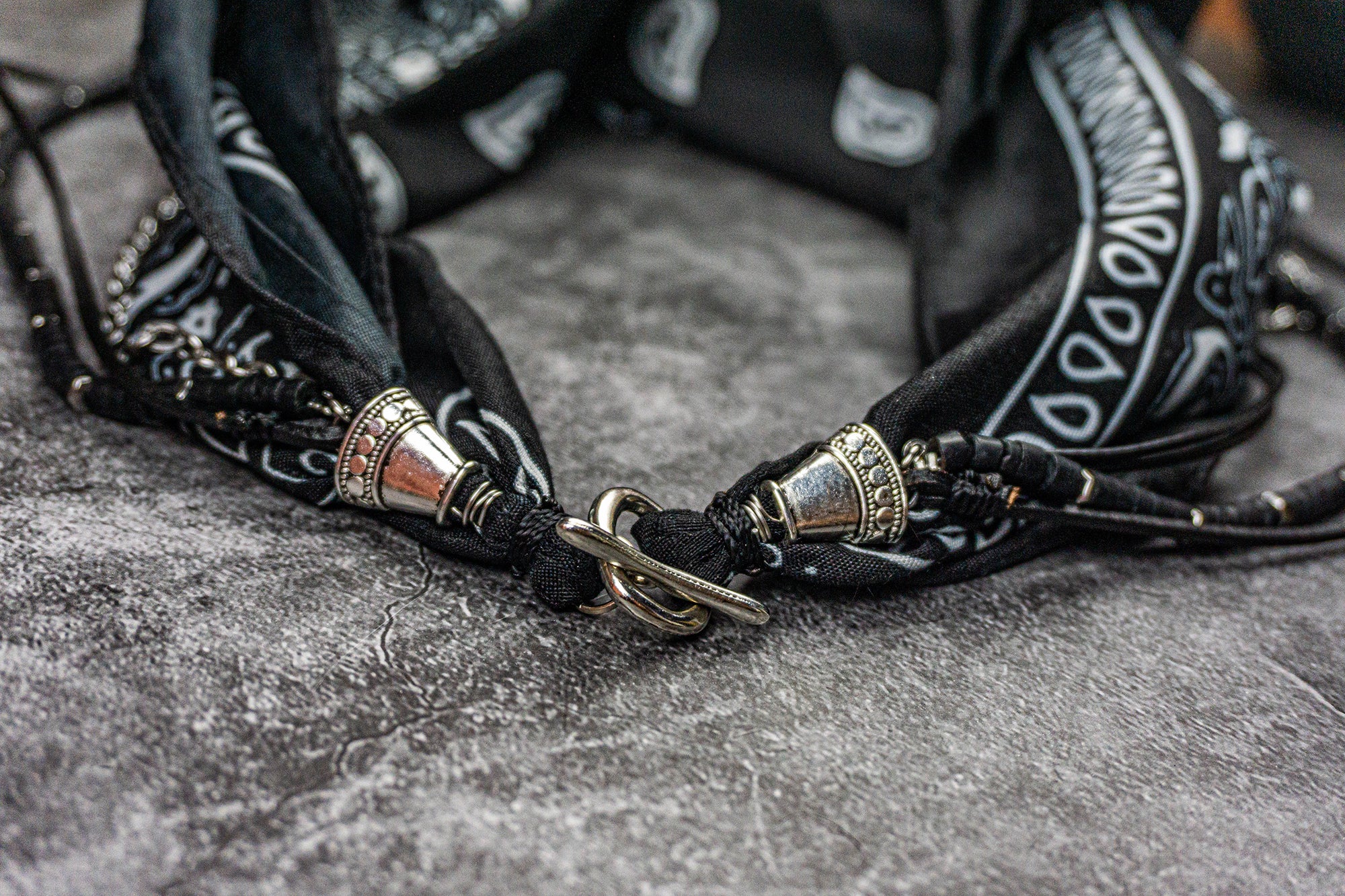 black bandana multistrand necklace made of stainless steel chain strand, black leather strand with arrowed pendant and black coconut strand