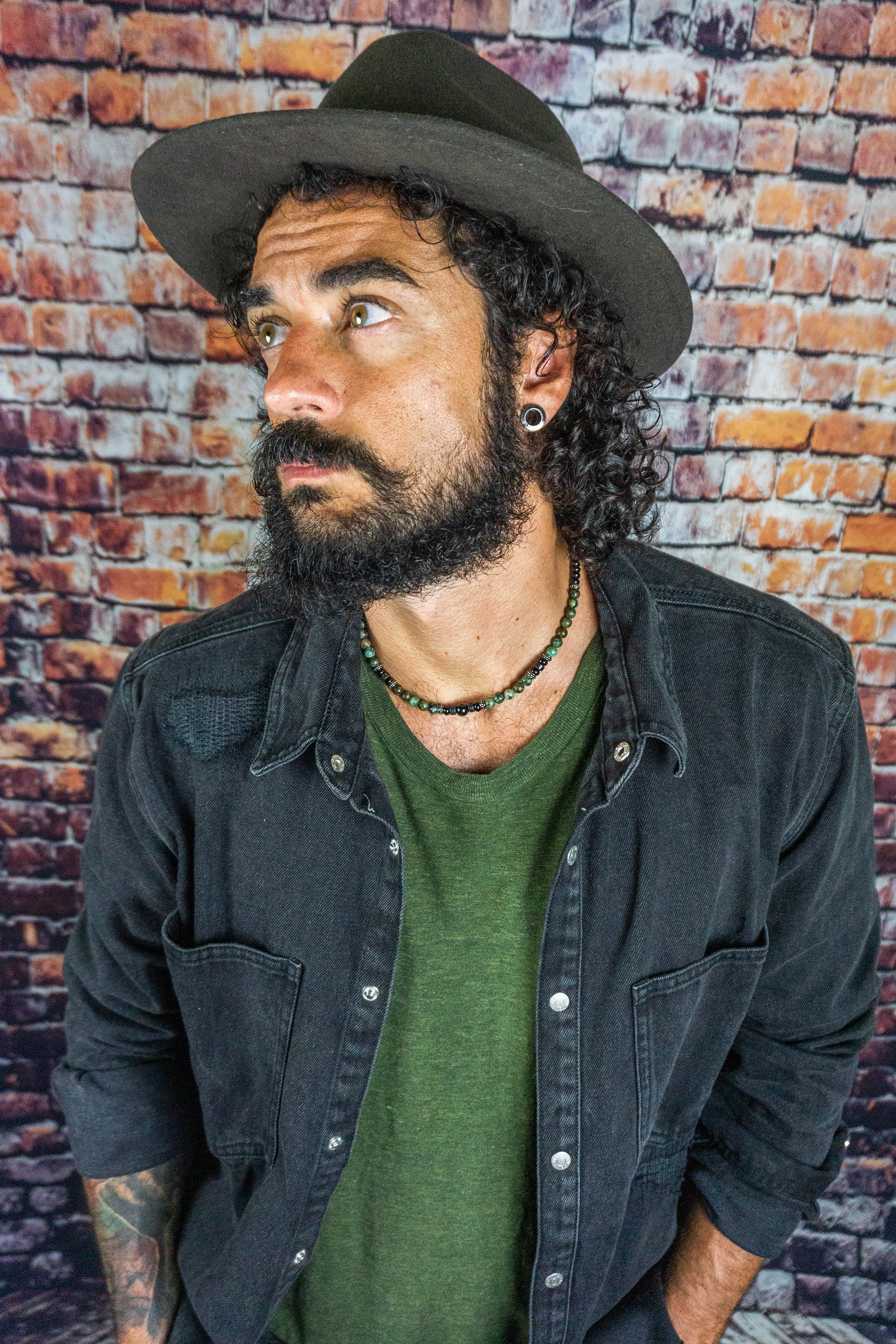 men waeringa hat and a black and green gemstone beads choker necklace with some stainless steel details