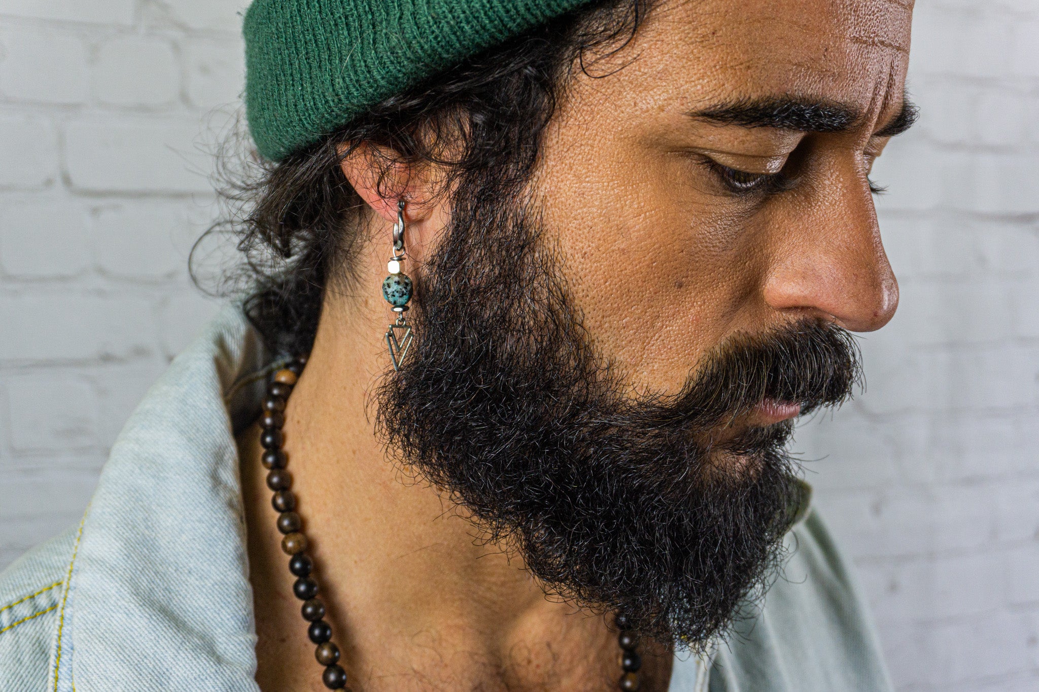 a hipster wearing a green beanie and a geometric dangling earring