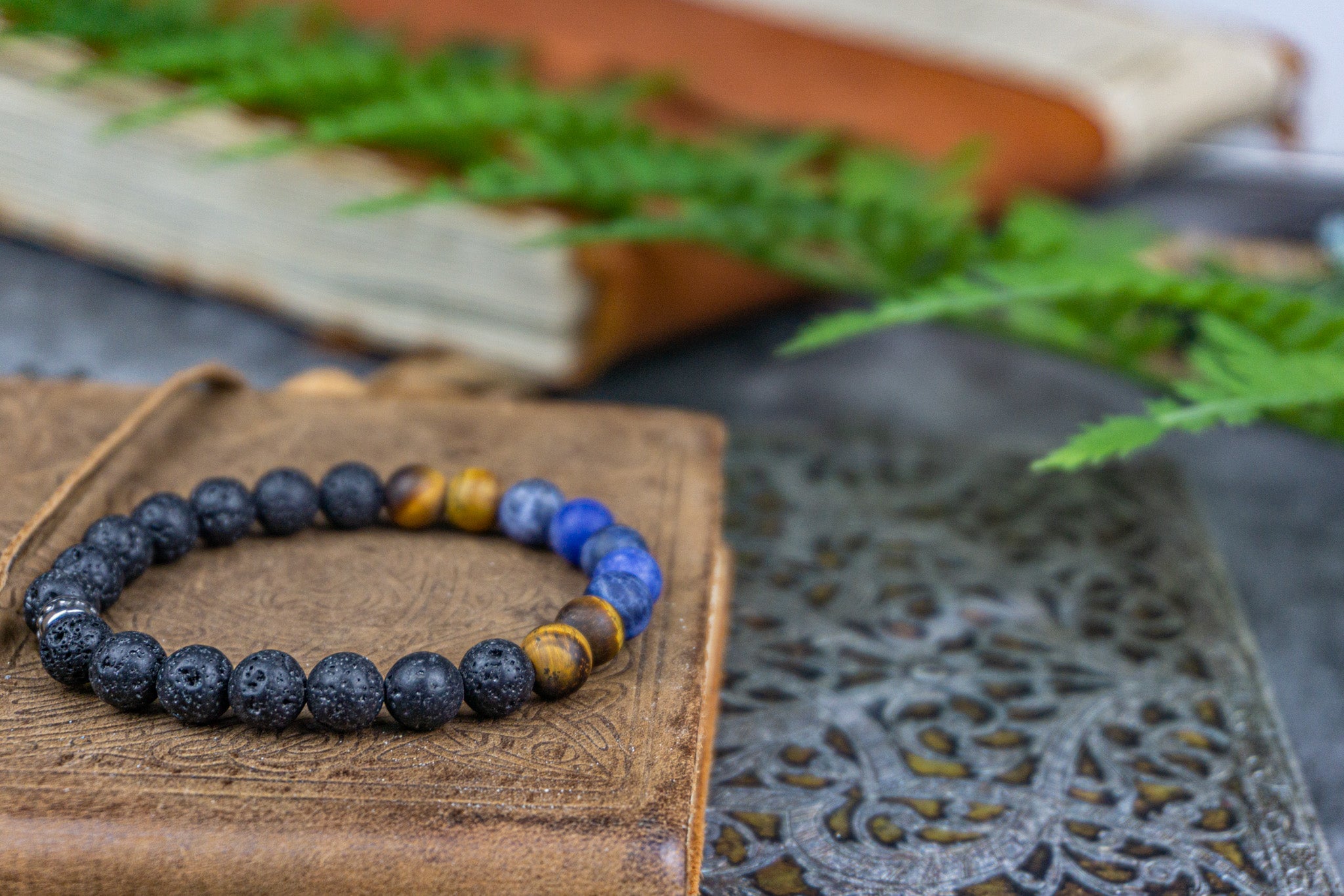 bracelet made of lava stone tiger eye sodalite, on on a book ,