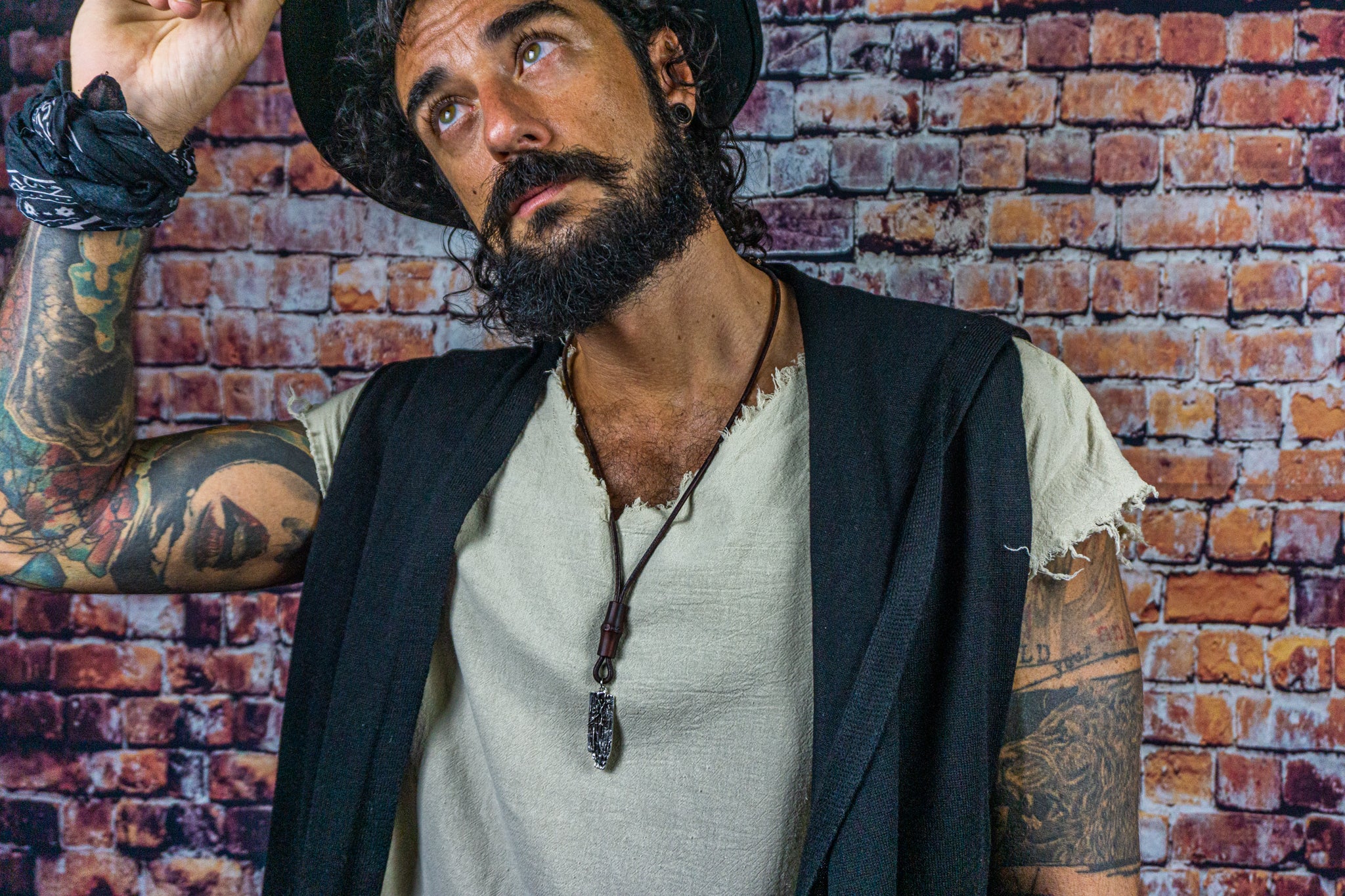 men wearing a long chunky leather necklace with a silver colored abstract pendant