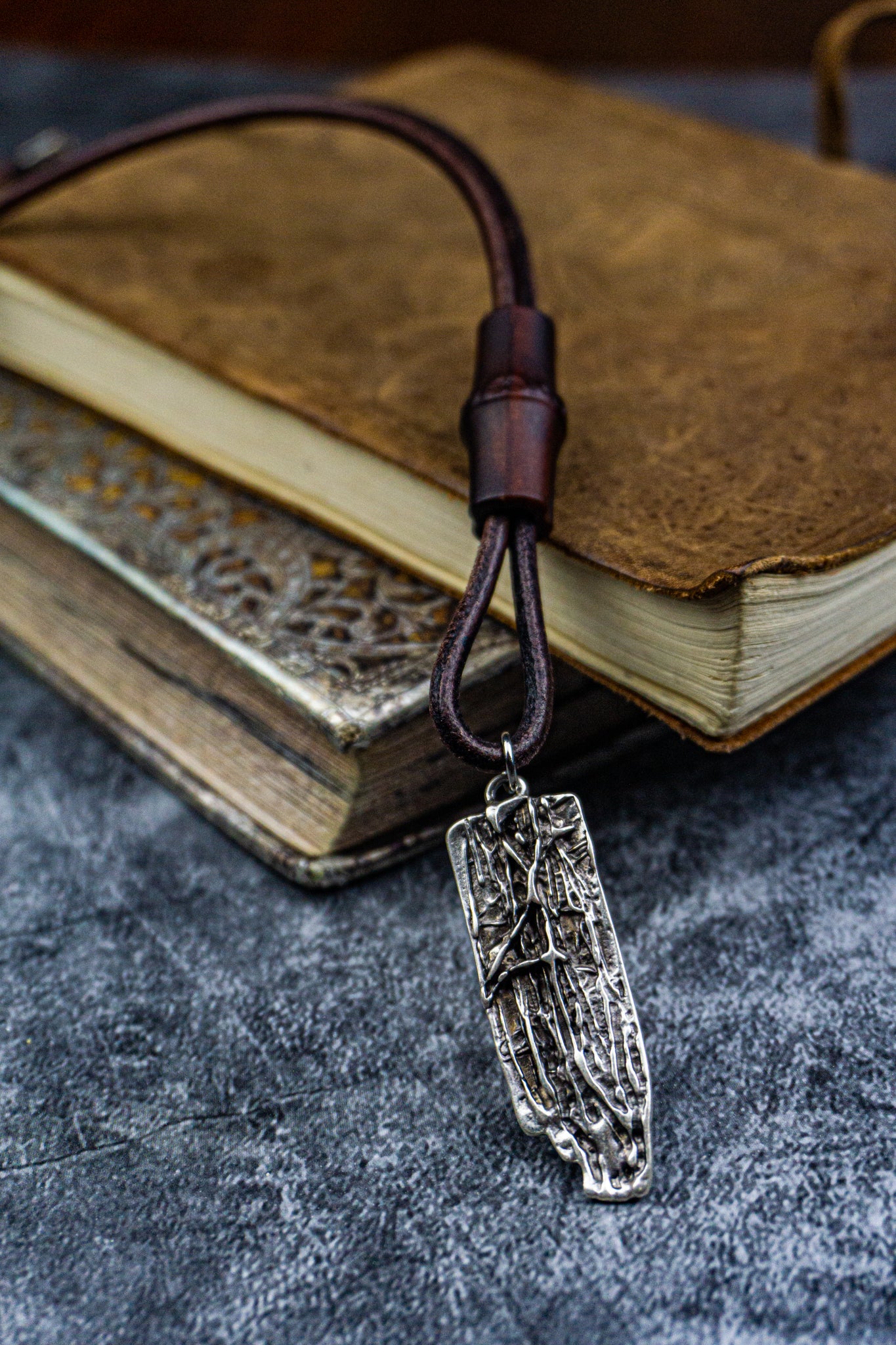 leather necklace with a silver colored tree bark texture pendant