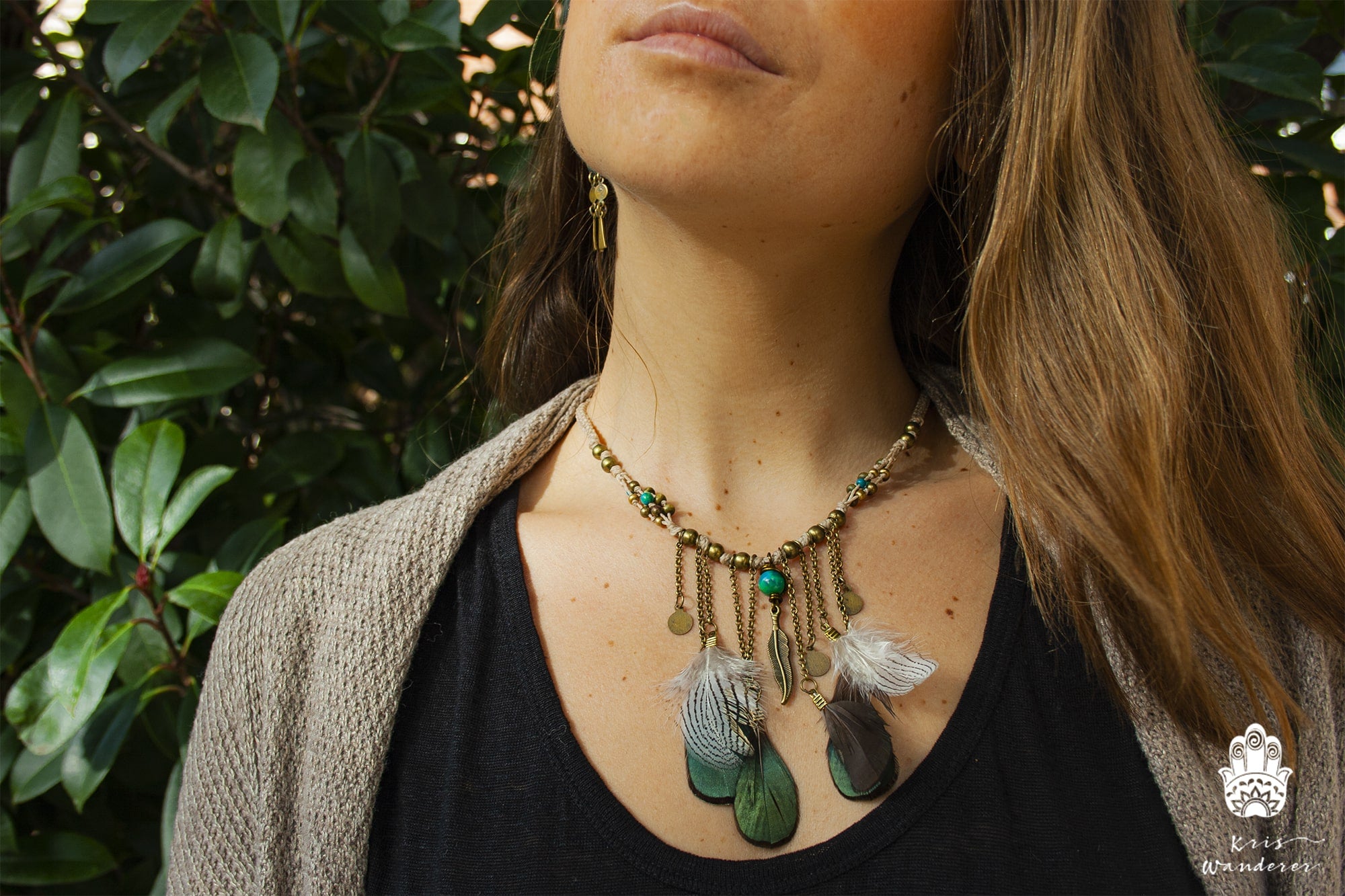 Person wearing a detailed necklace with feathers and beads against a natural background