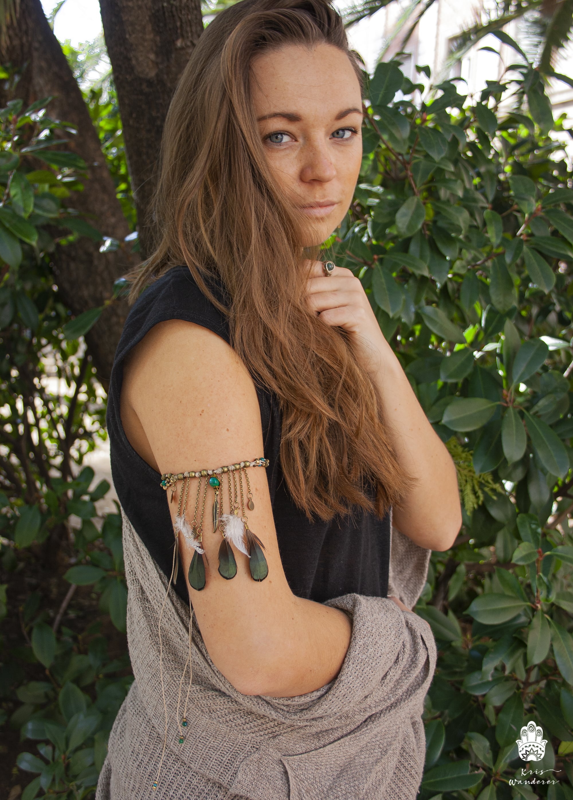 Woman with arm decorations standing in front of green foliage