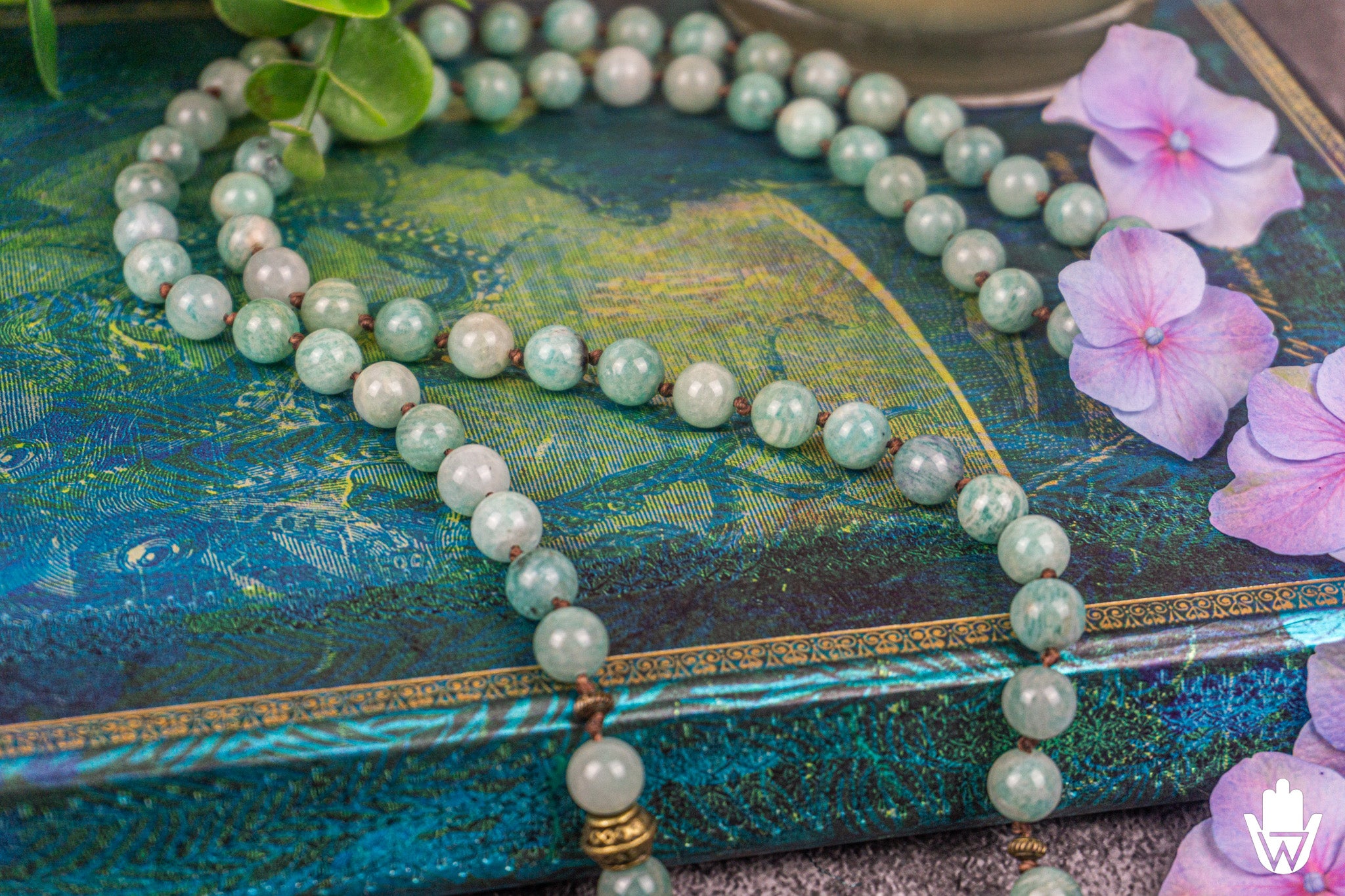 close up of a mala necklace on a blue surface decrated with flowers