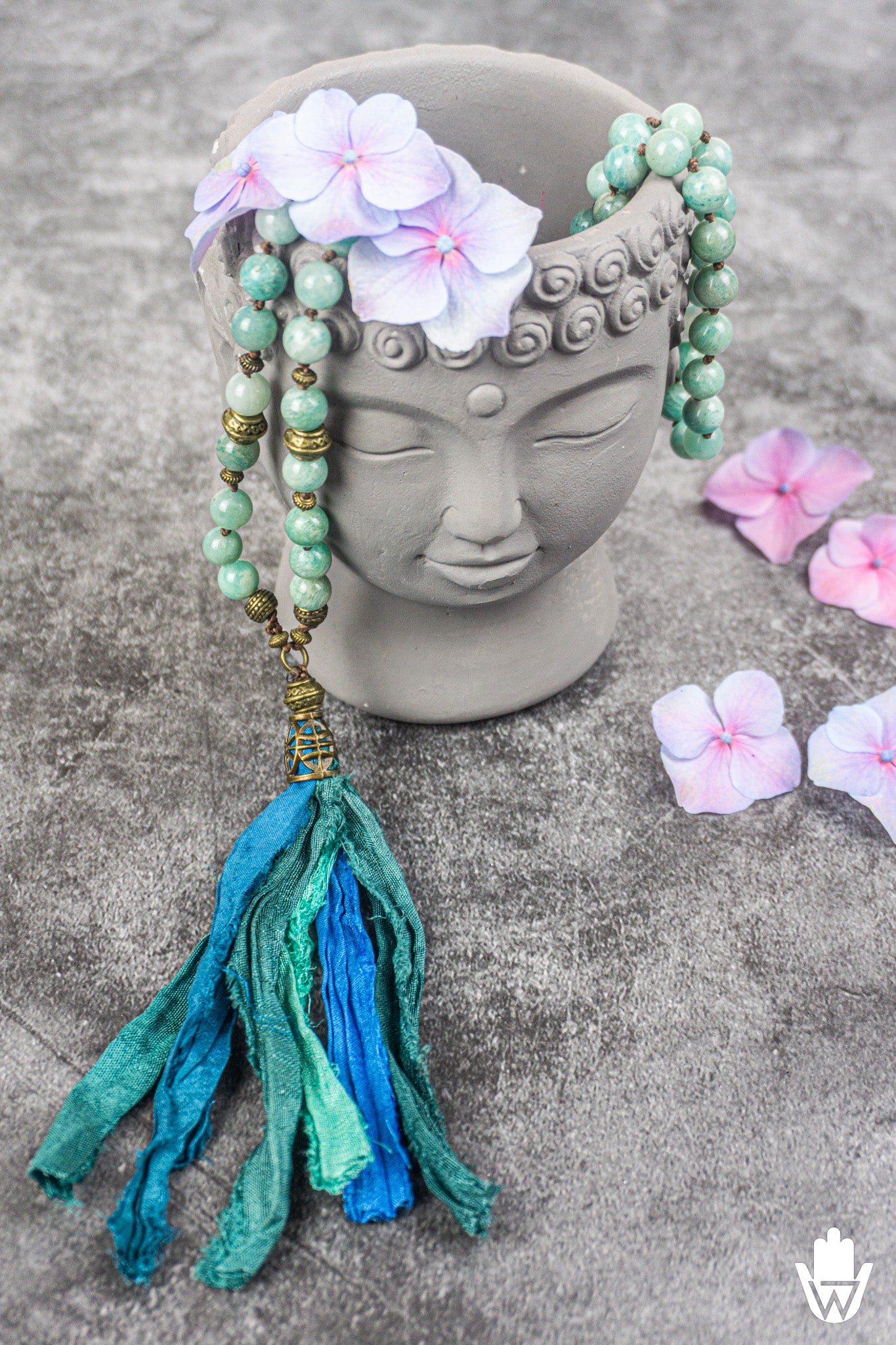 beautiful blue tassel necklace on a spiritual background with a buddha head and flowers