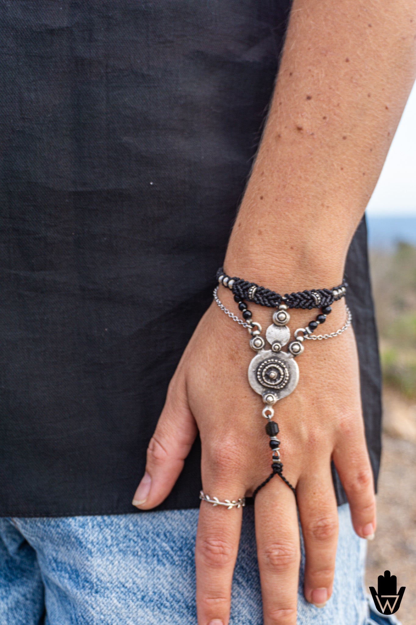Hand wearing layered bracelets with a blurred natural background-wander jewellery
