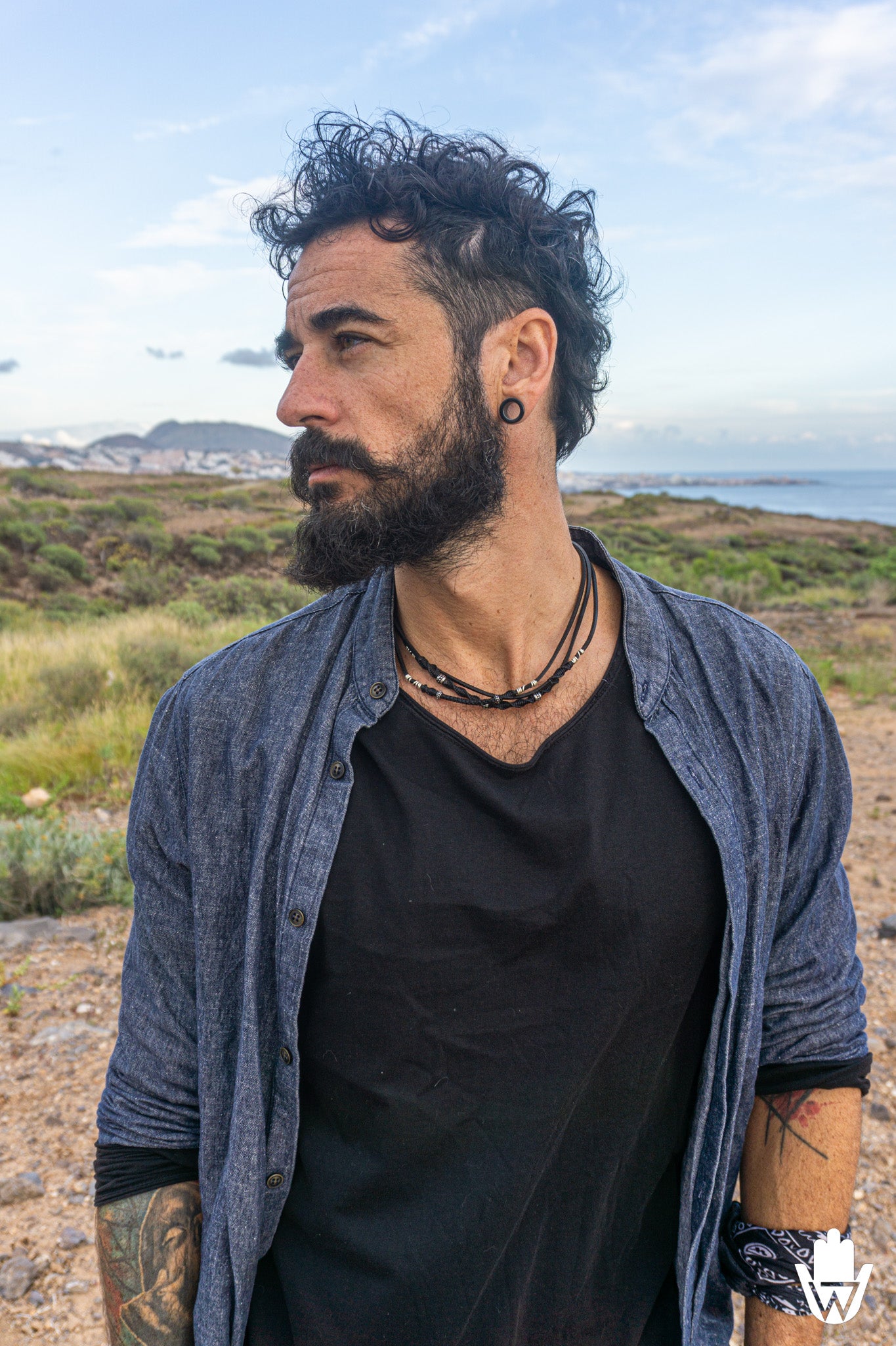 mens with jeans shrt and a layering choker necklace with desrtic landscape