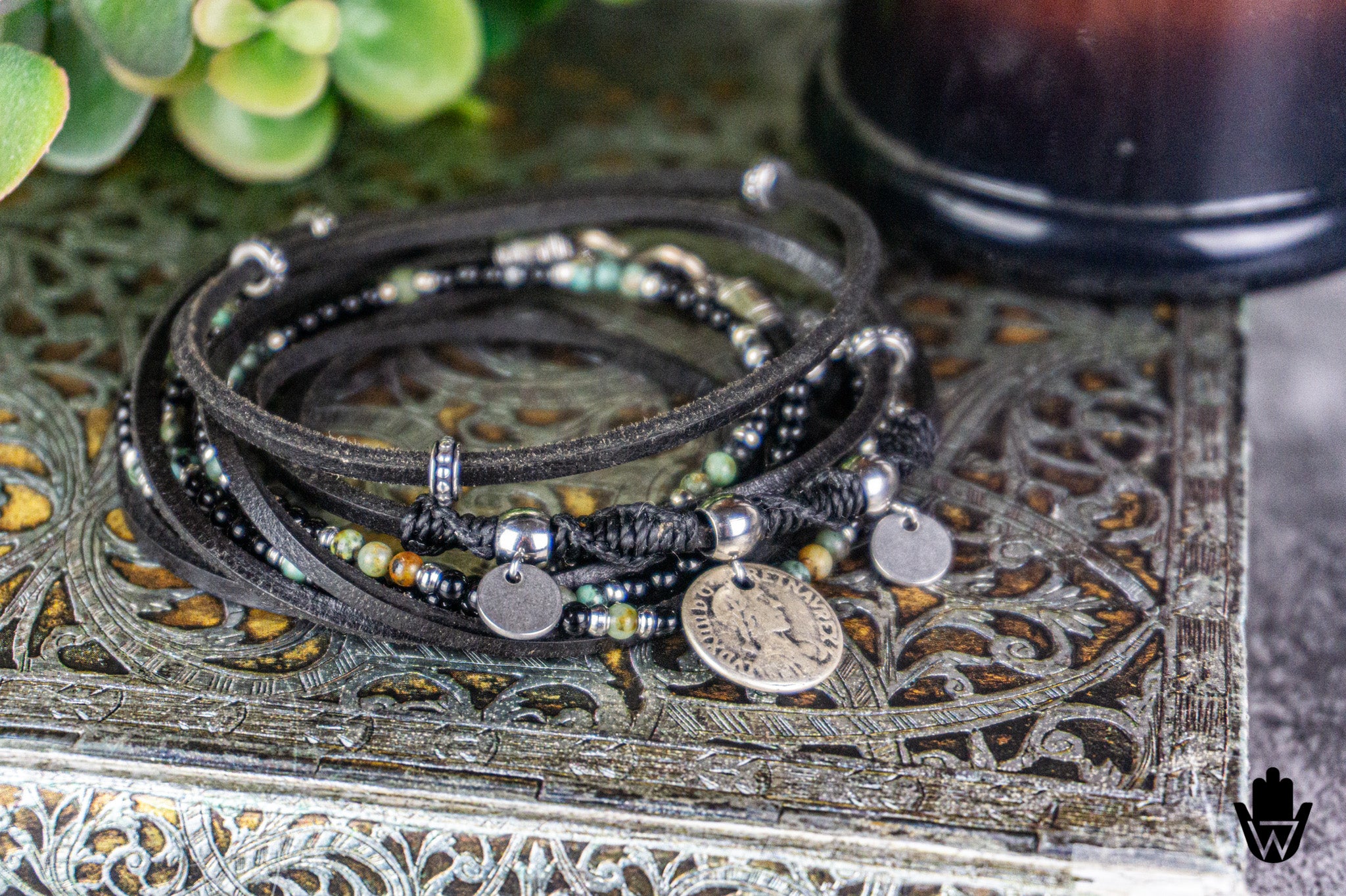 Stack of beaded bracelets with metal charms on a decorative surface
