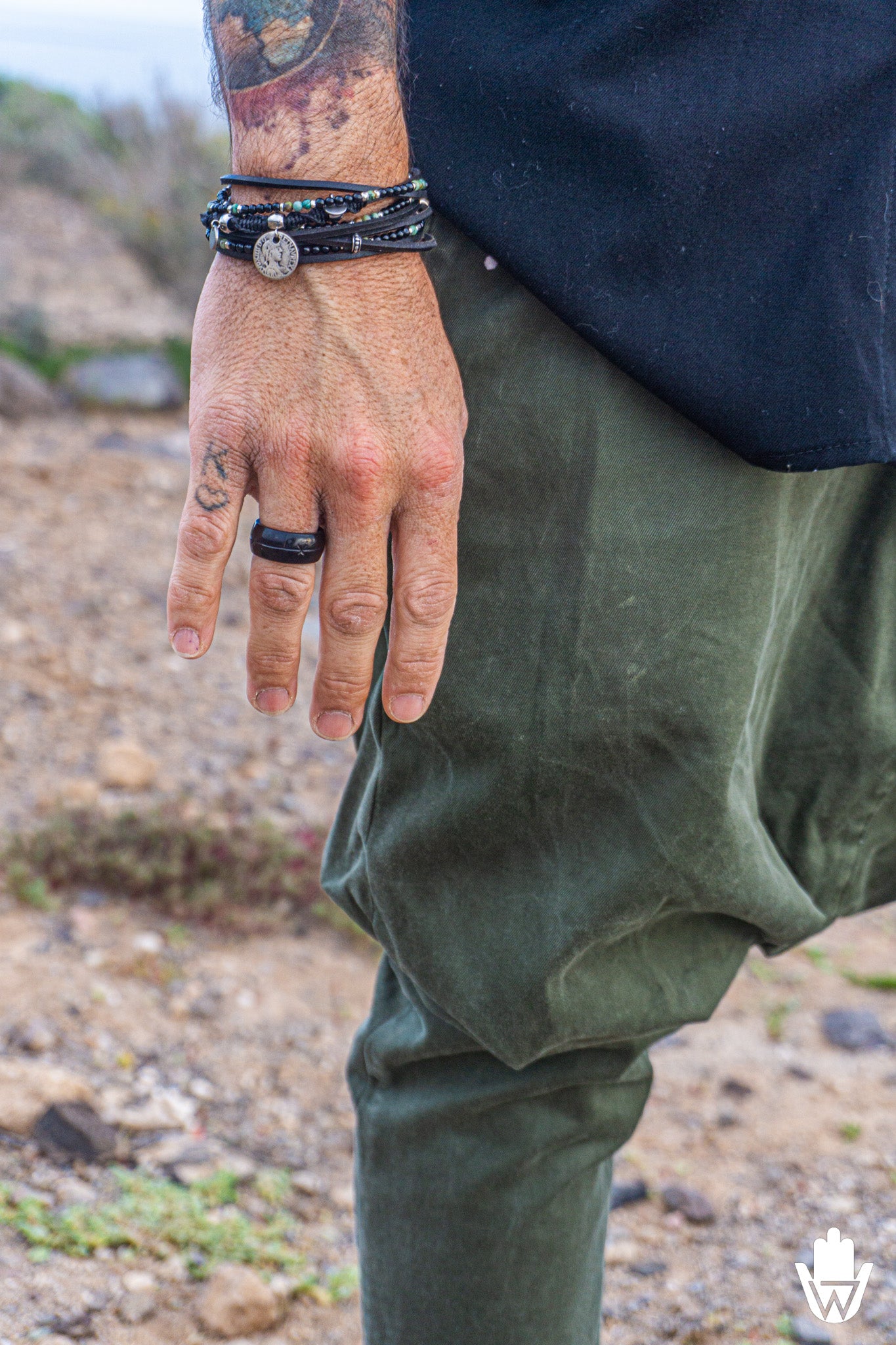 Person wearing green pants and multi layer bracelet on a natural background