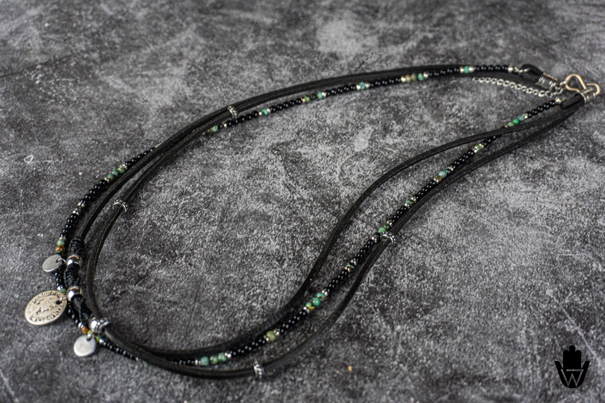 Black beaded multistrand bracelet with charms on a gray textured surface