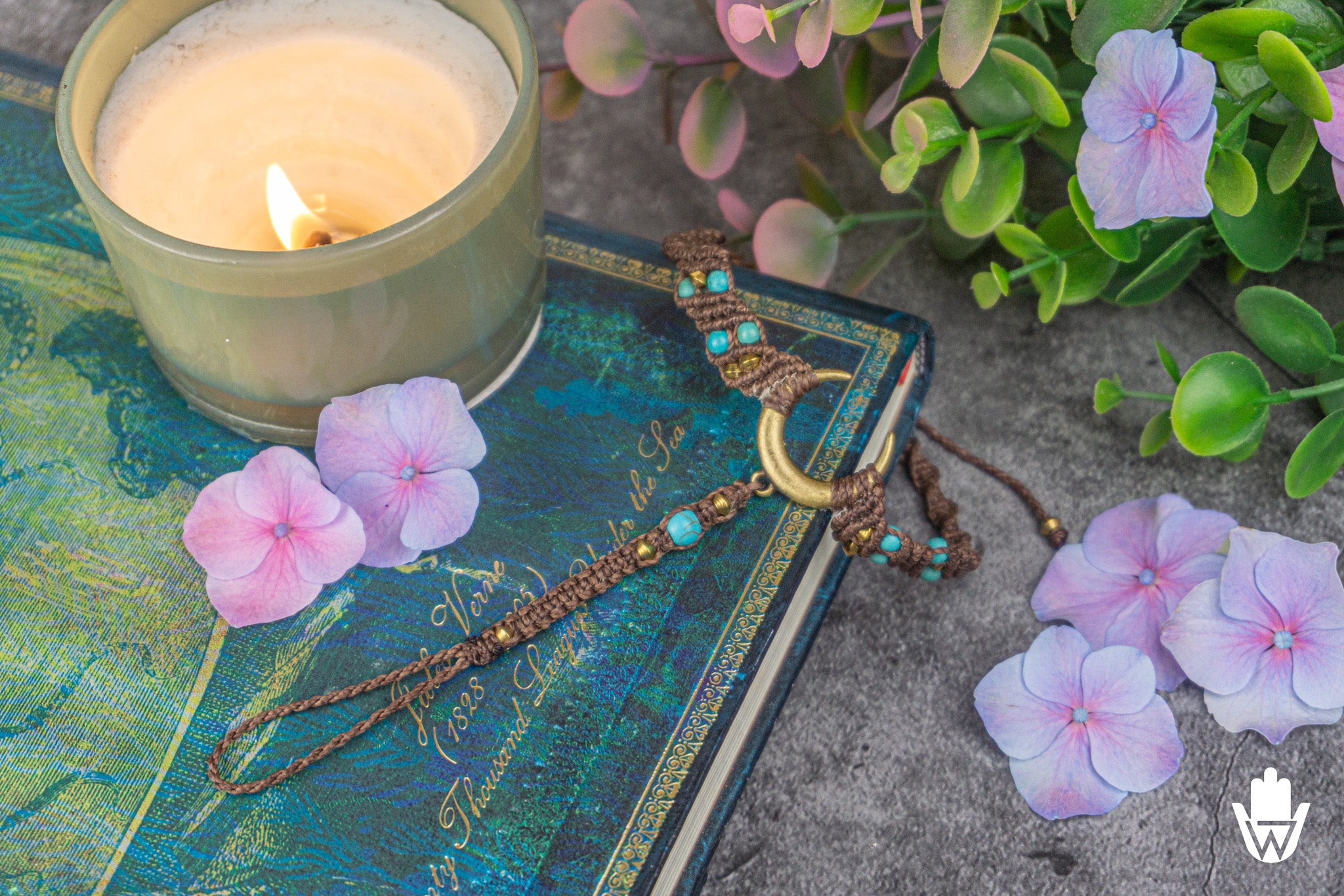 brown macrame moon charm bracelet in a decorative background with flowers and candle and book