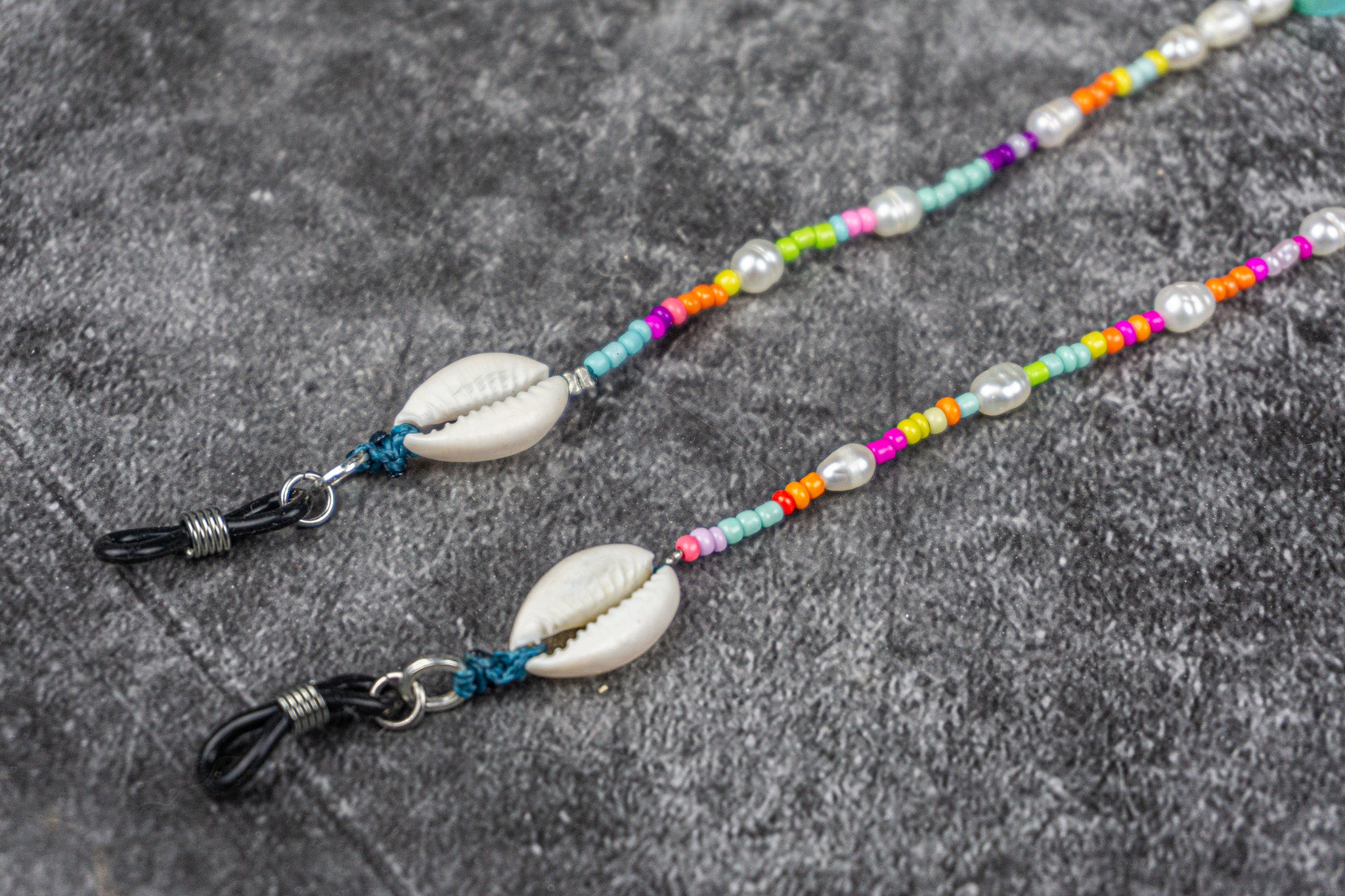 close up to the cowrie shell at the end of the colorful beaded glasses chain- wander jewellery