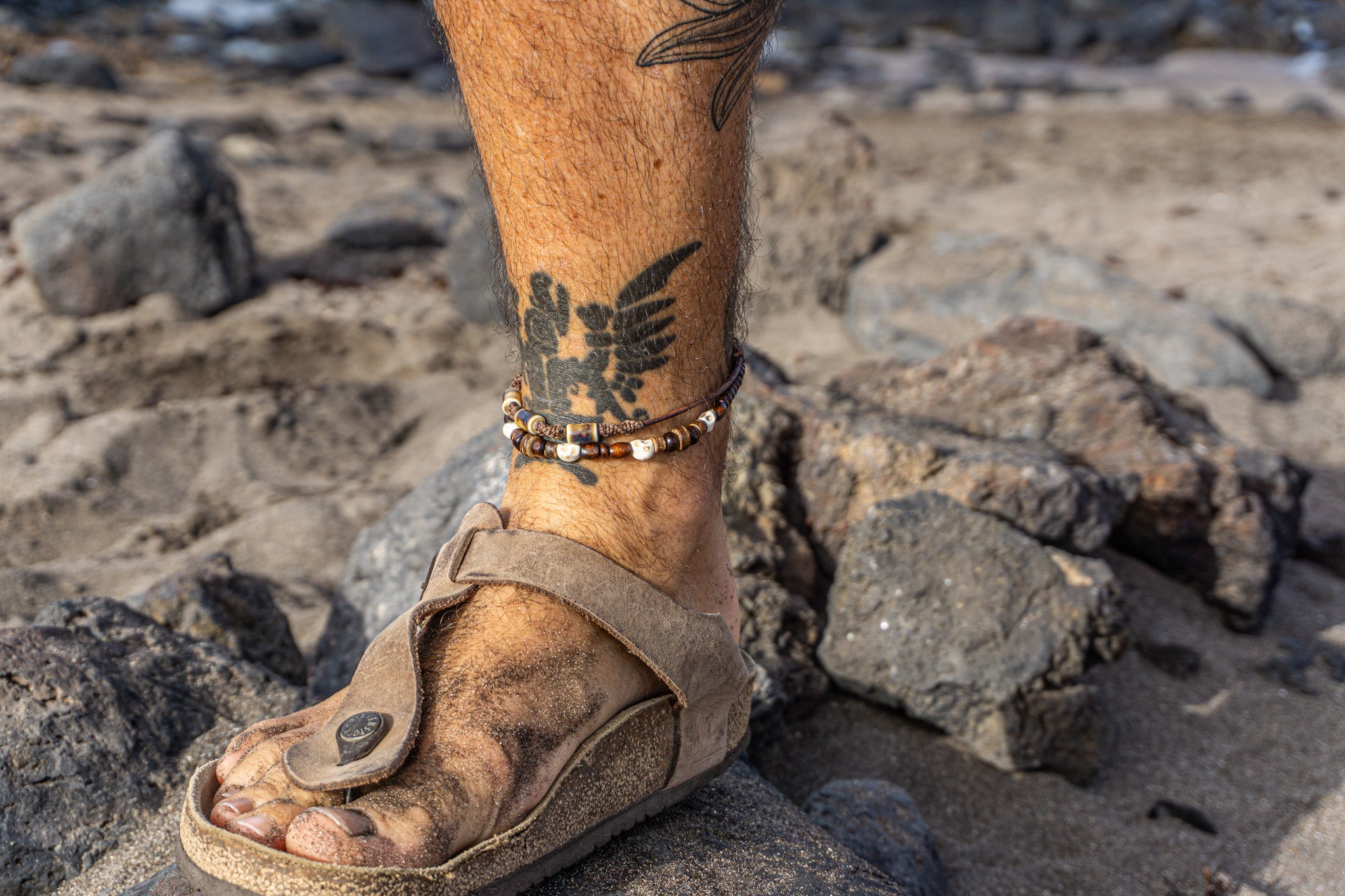 Mens layered leather anklet with ceramic beads, pirate skull charms, and wooden and coconut accents – Wander Jewellery