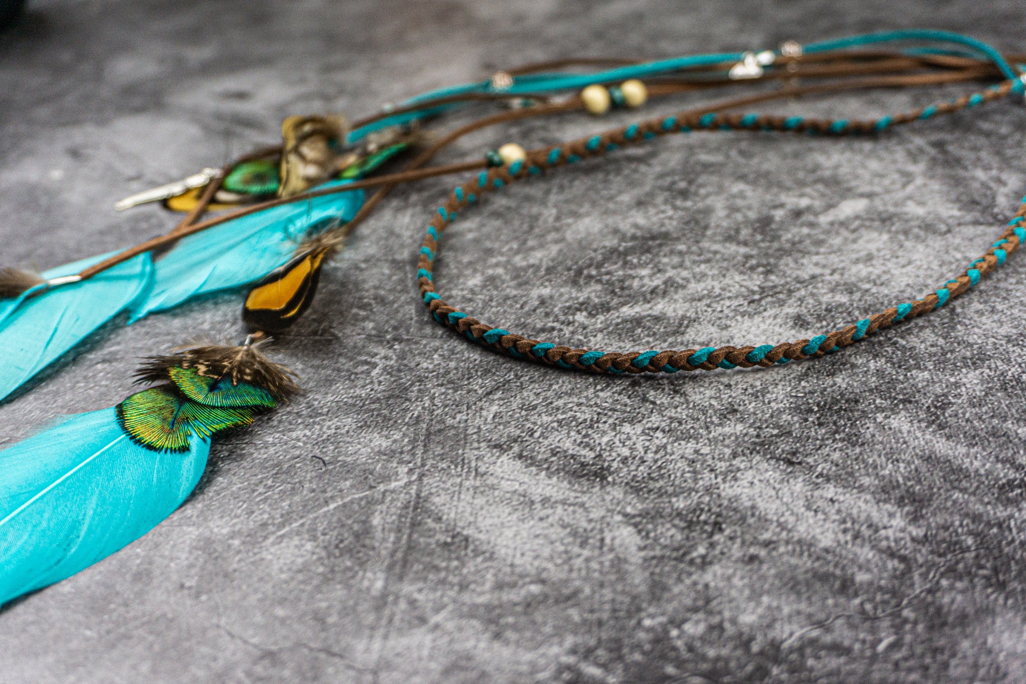 leather headband with feathers on a textured gray surface