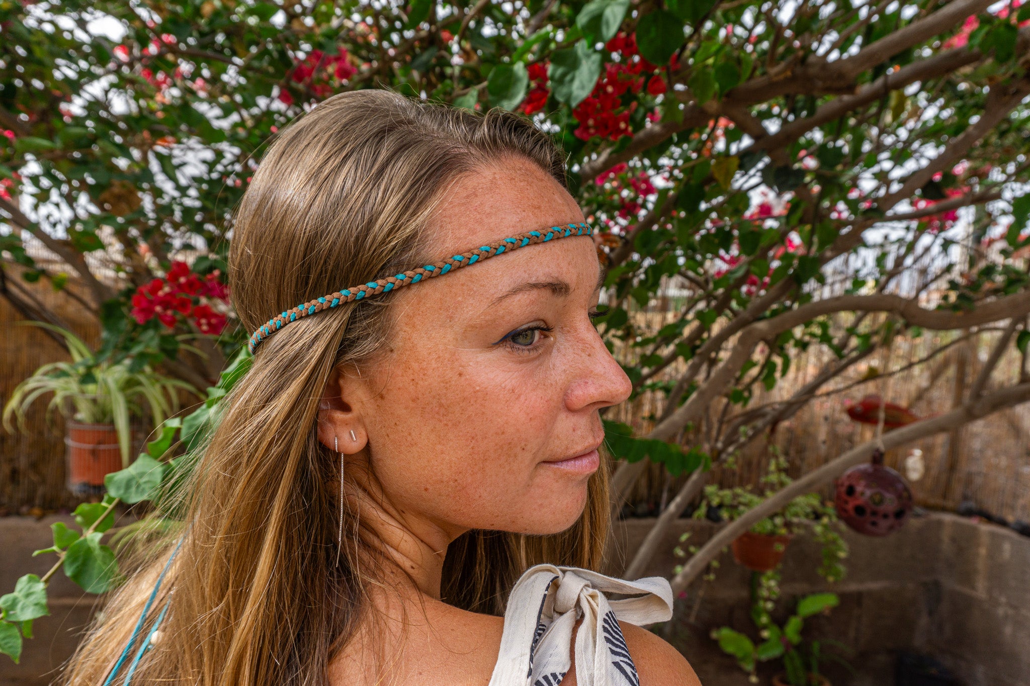 Woman with a headband in front of a flowering plant