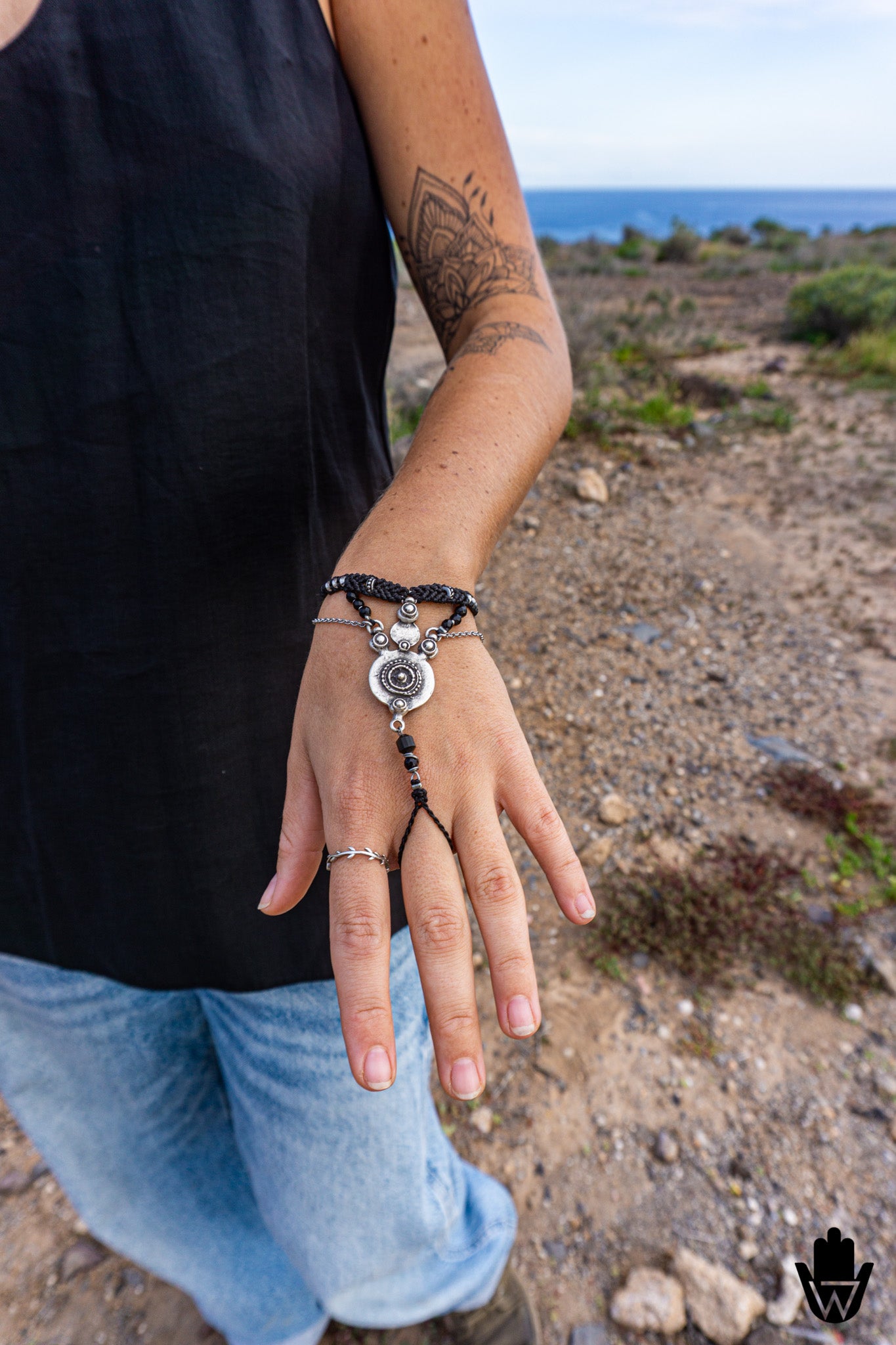 Person wearing a black hand bracelet with a chain against a scenic background