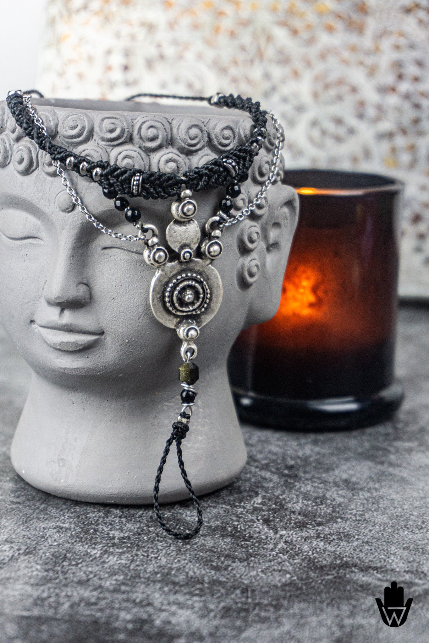 Decorative bracelet with beads on a mannequin head next to a candle