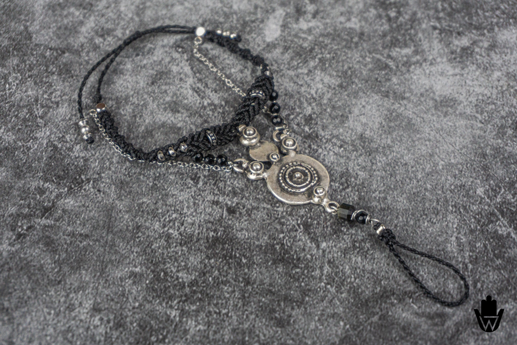 Black beaded ring bracelet with decorative elements on a textured gray surface