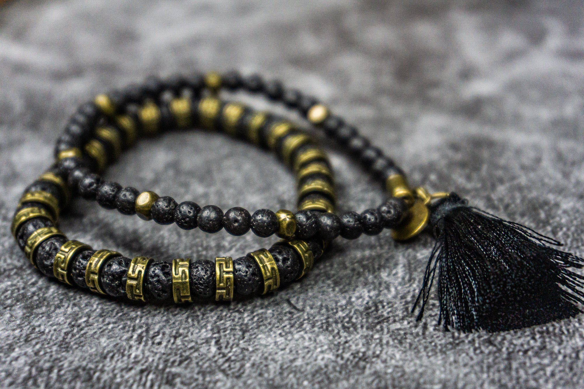 black lava stone bracelet set made of one bigger brass and lava stone bracelet and one with small lava beads and a tassel dangle- wander jewellery