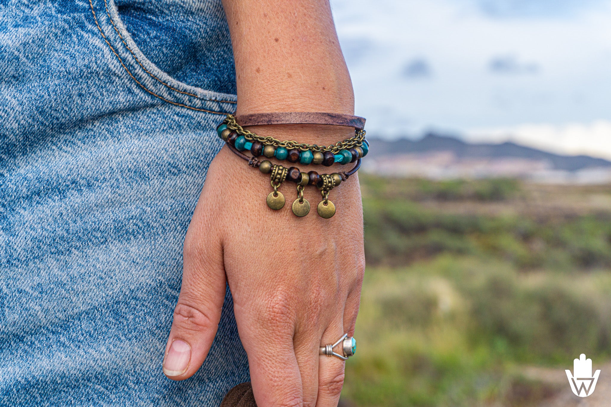 Person wearing multistrand bracelet set on a wrist with a scenic background