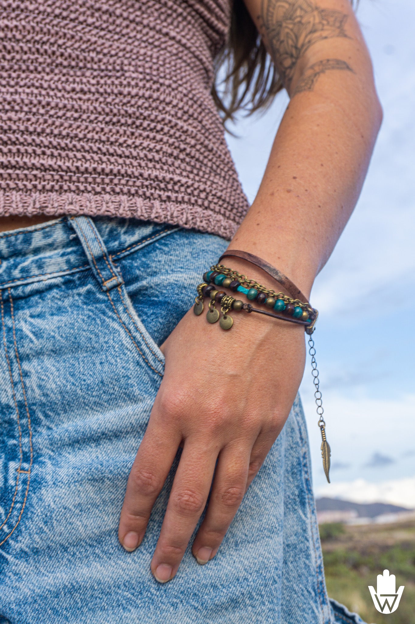 Person wearing a boho multi layer bracelet set on a wrist with a blurred natural background
