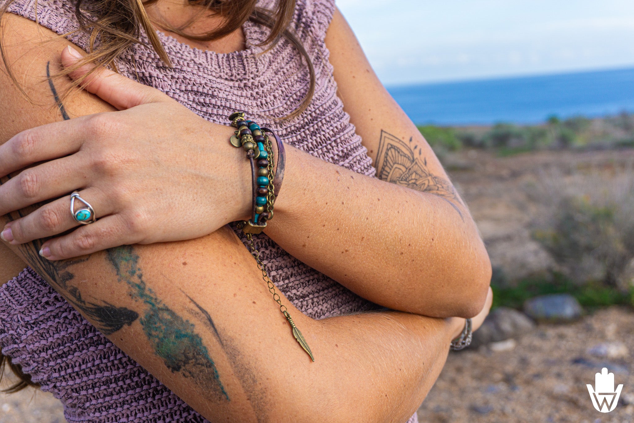 Person with tattoos and jewelry against a scenic background