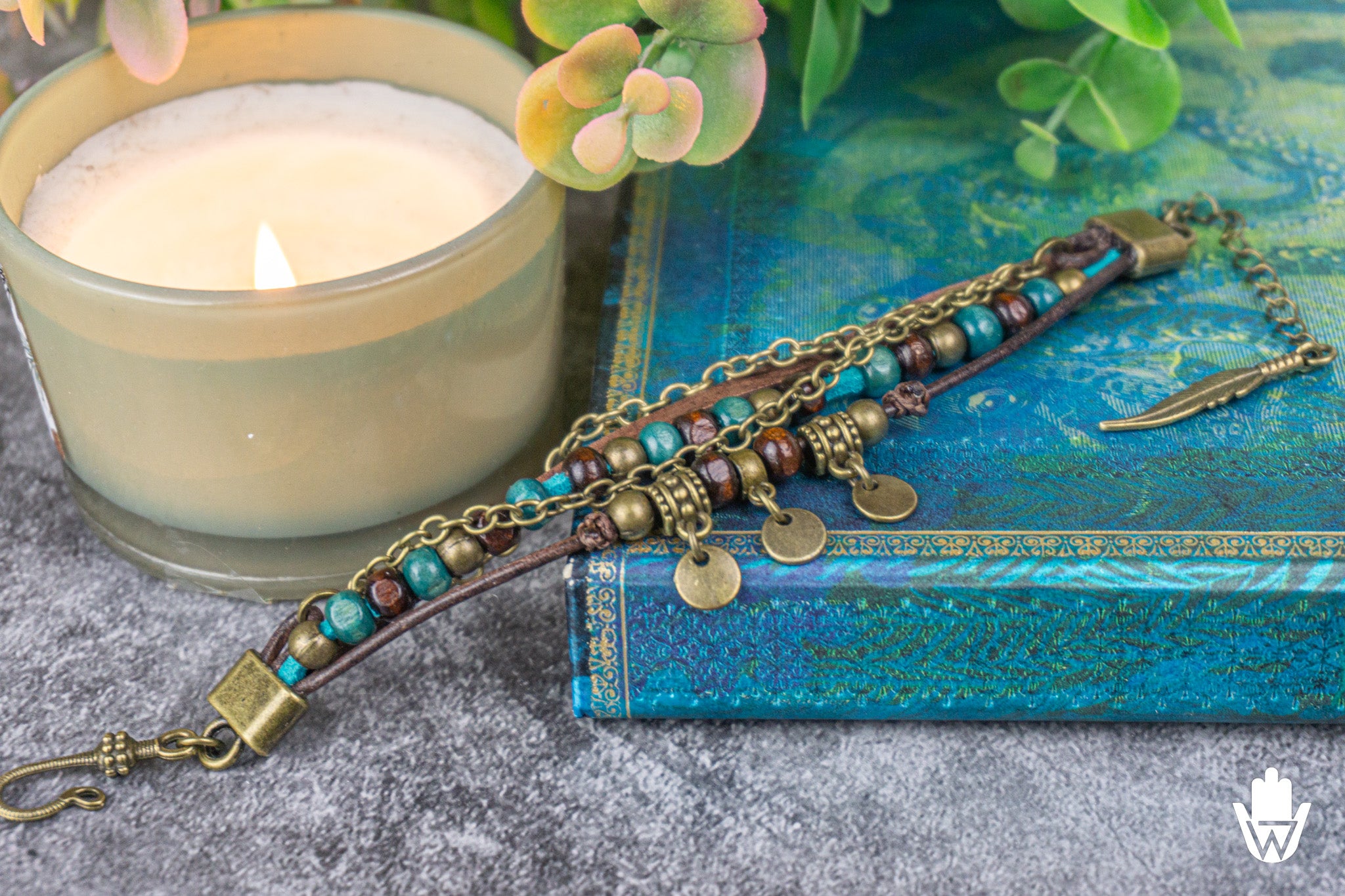 Bracelet with beads chain and leather on a blue book next to a candle