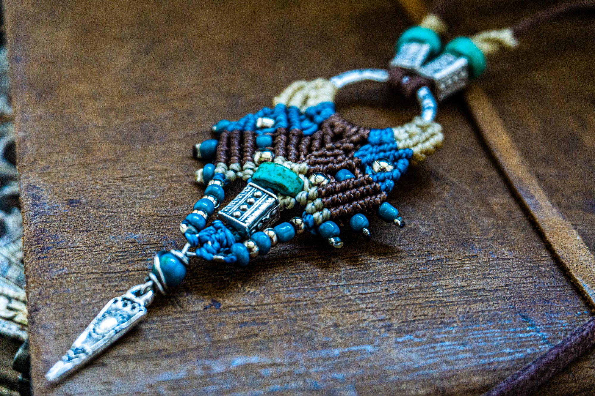 Decorative brooch with blue and brown beads on a wooden surface