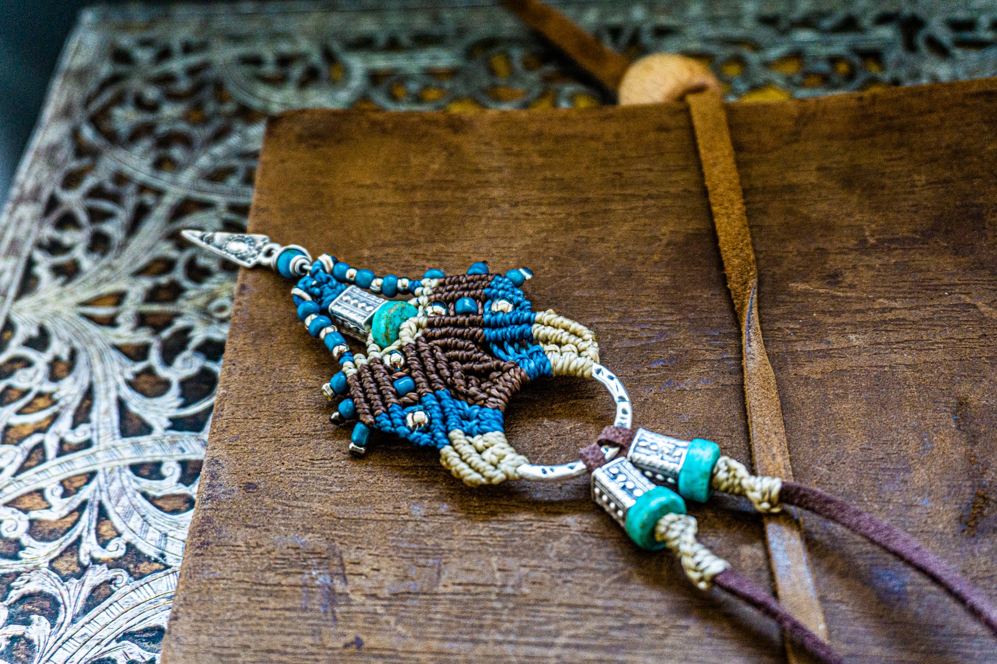 Decorative bogo pendant necklace with intricate design on a wooden surface