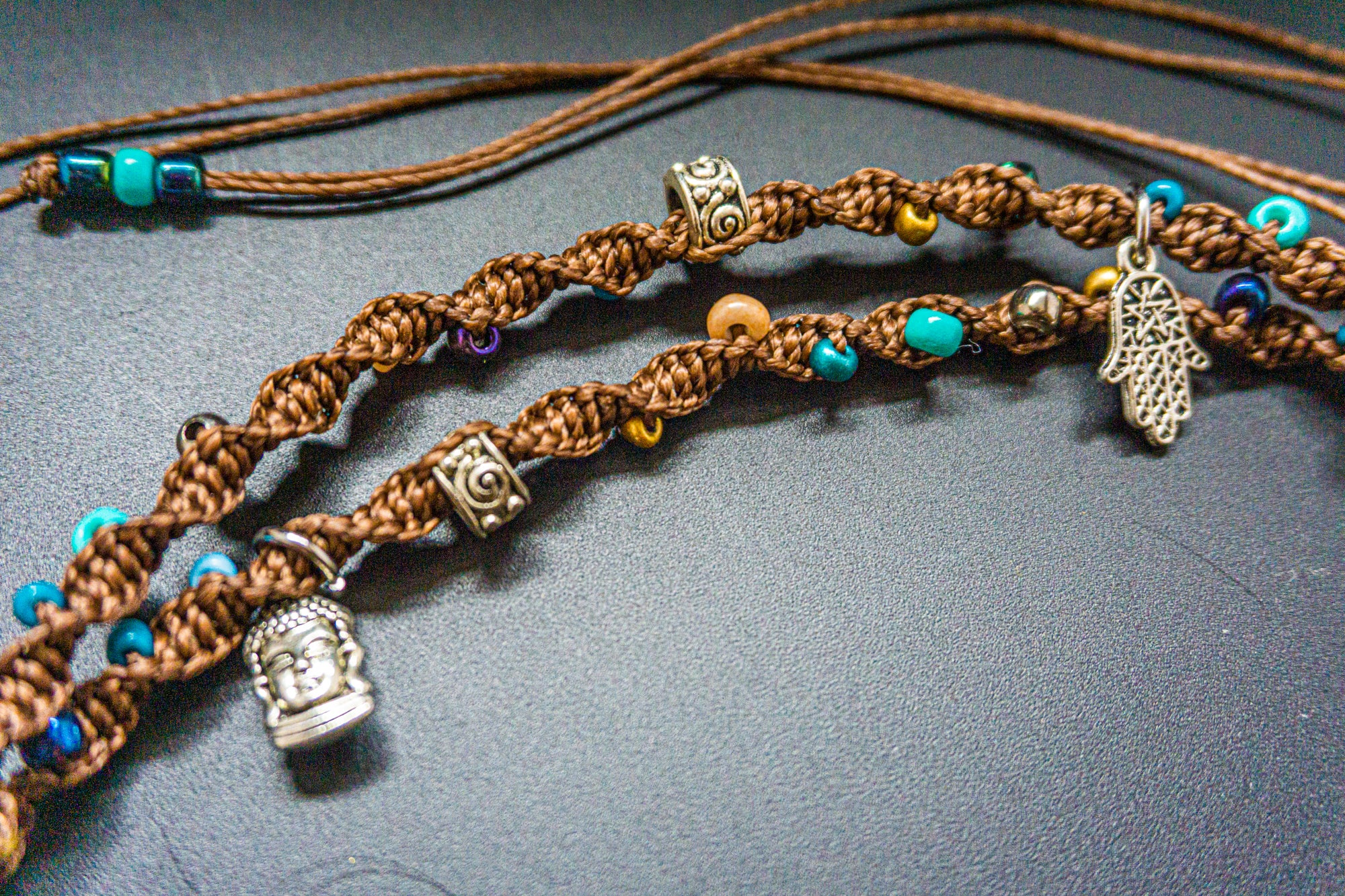 Braided brown cord with decorative beads and charms on a dark surface