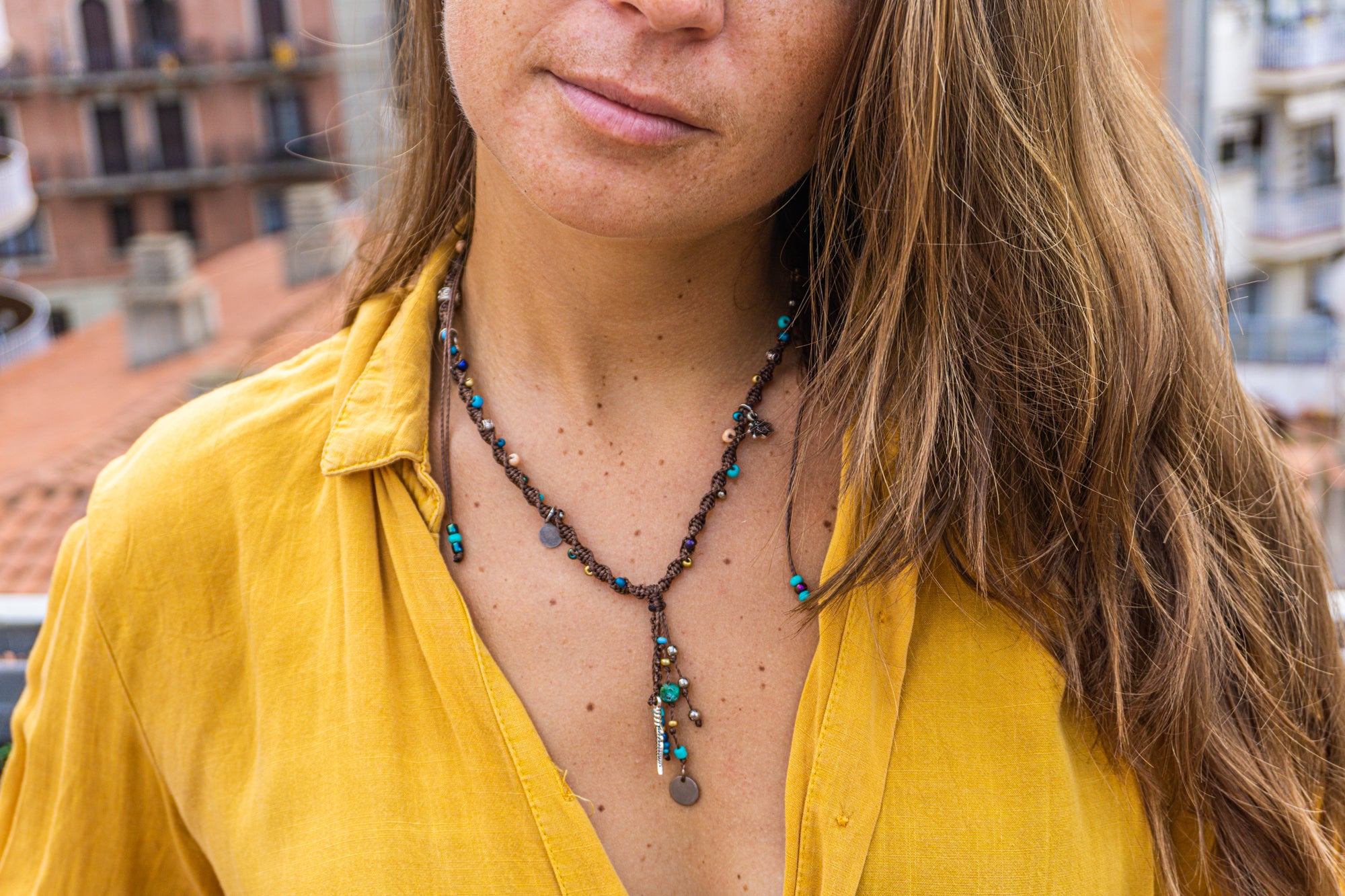 Person wearing a yellow shirt and a necklace with a blurred background