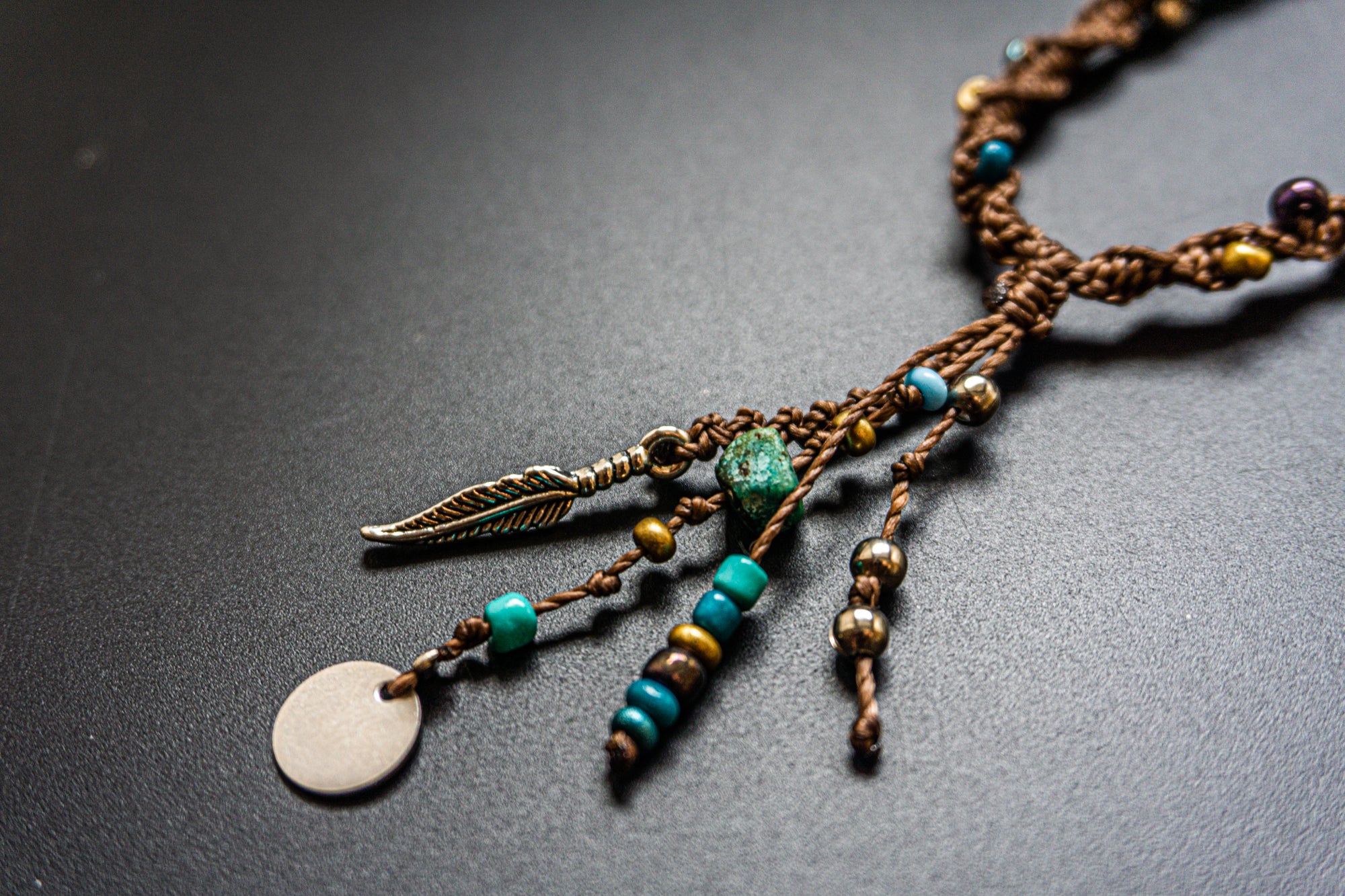 Necklace with beads and leaf charm on a dark surface