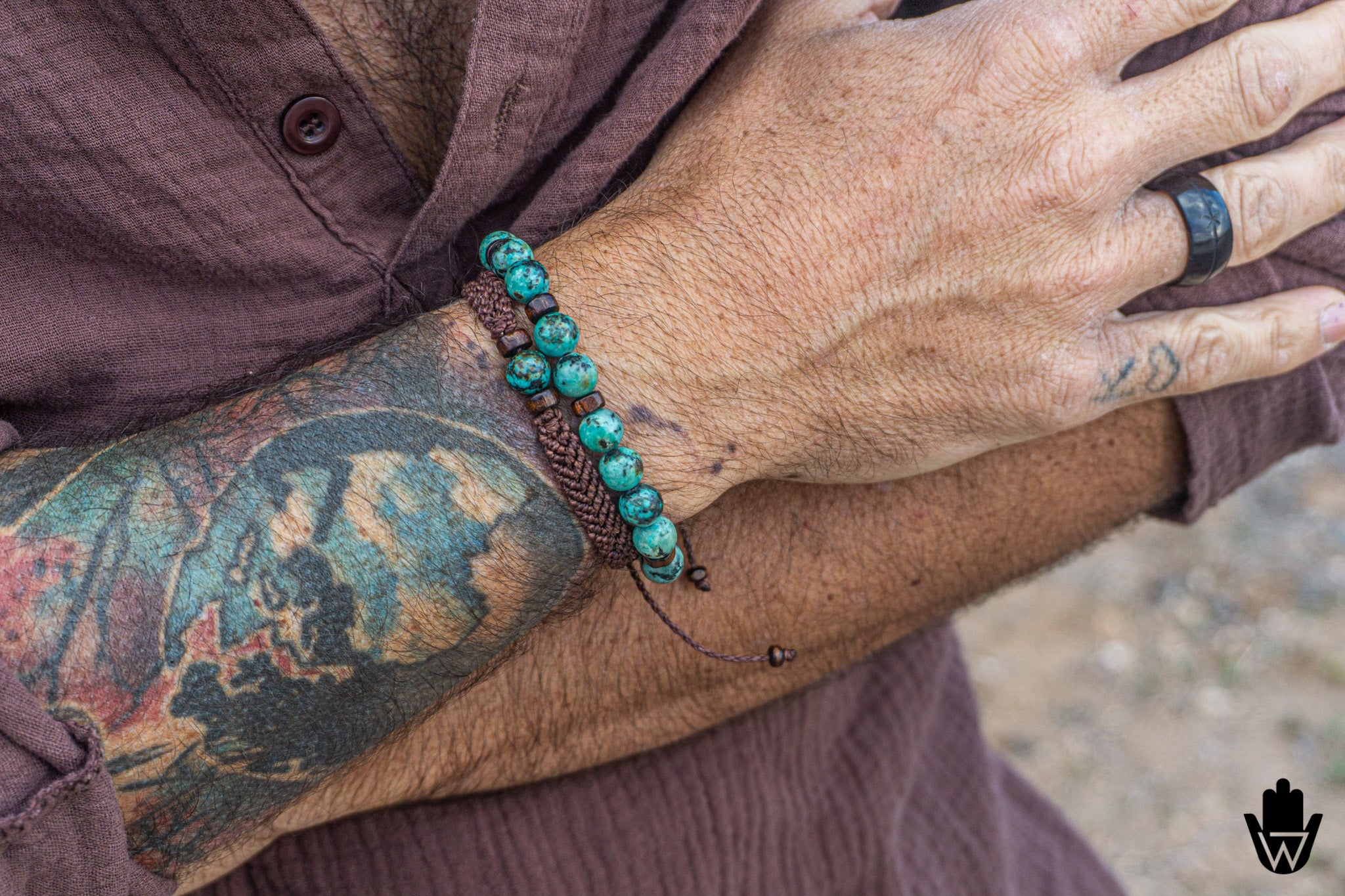 Close-up of a person's arm with tattoos wearing a turquoise beaded  bracelet set