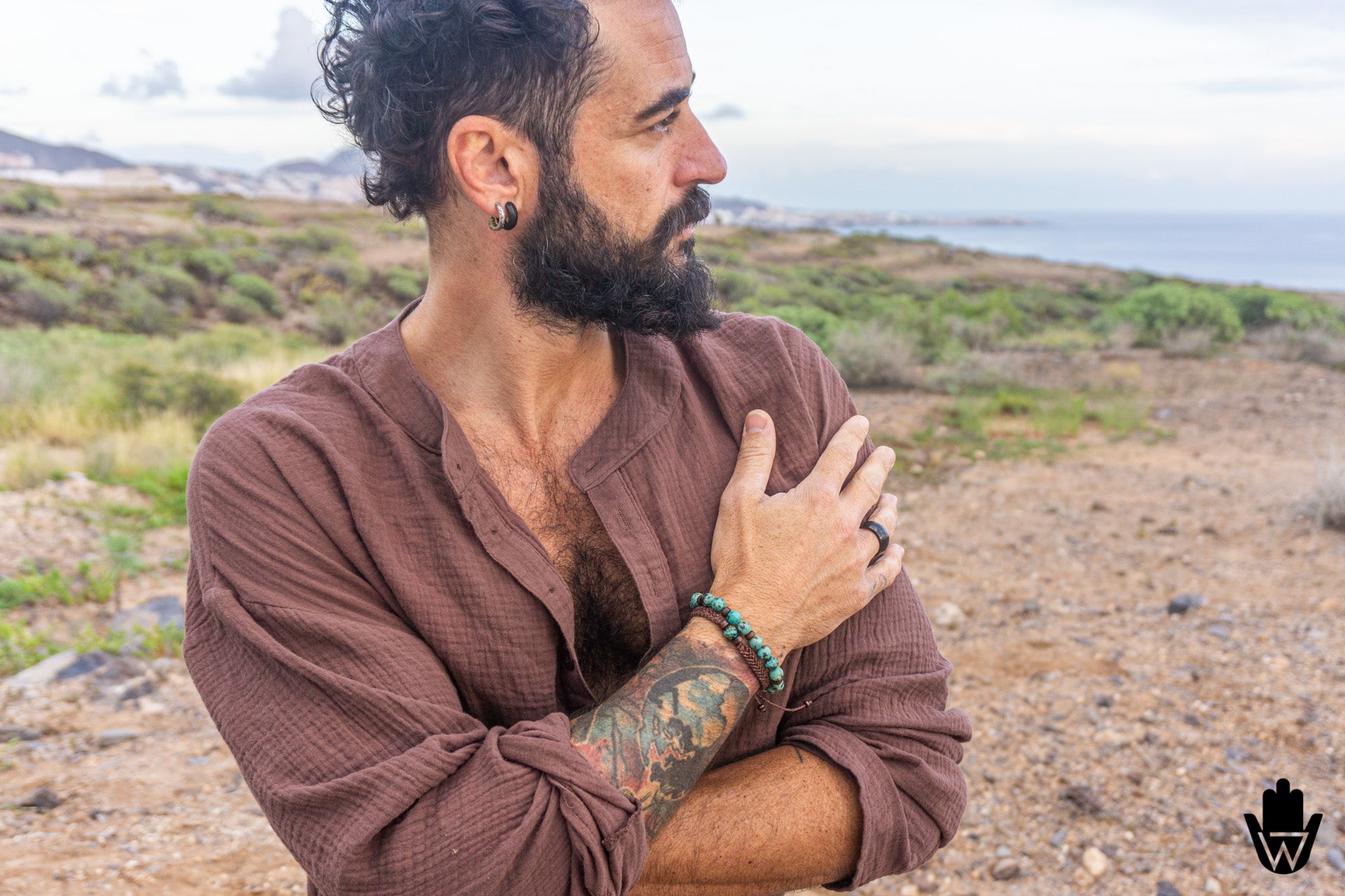 Man with a beard and tattoos sitting outdoors in a natural setting