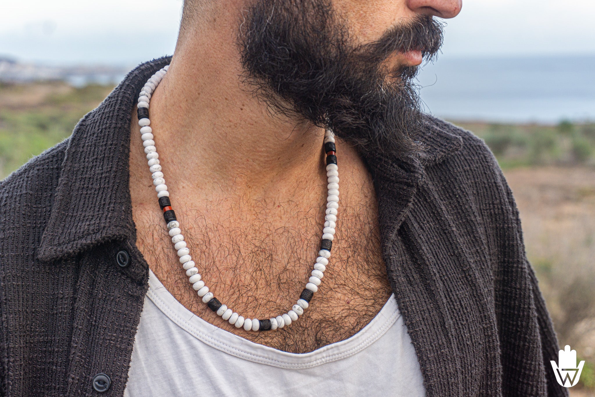 close up of a man wearing a long white gemstone necklace