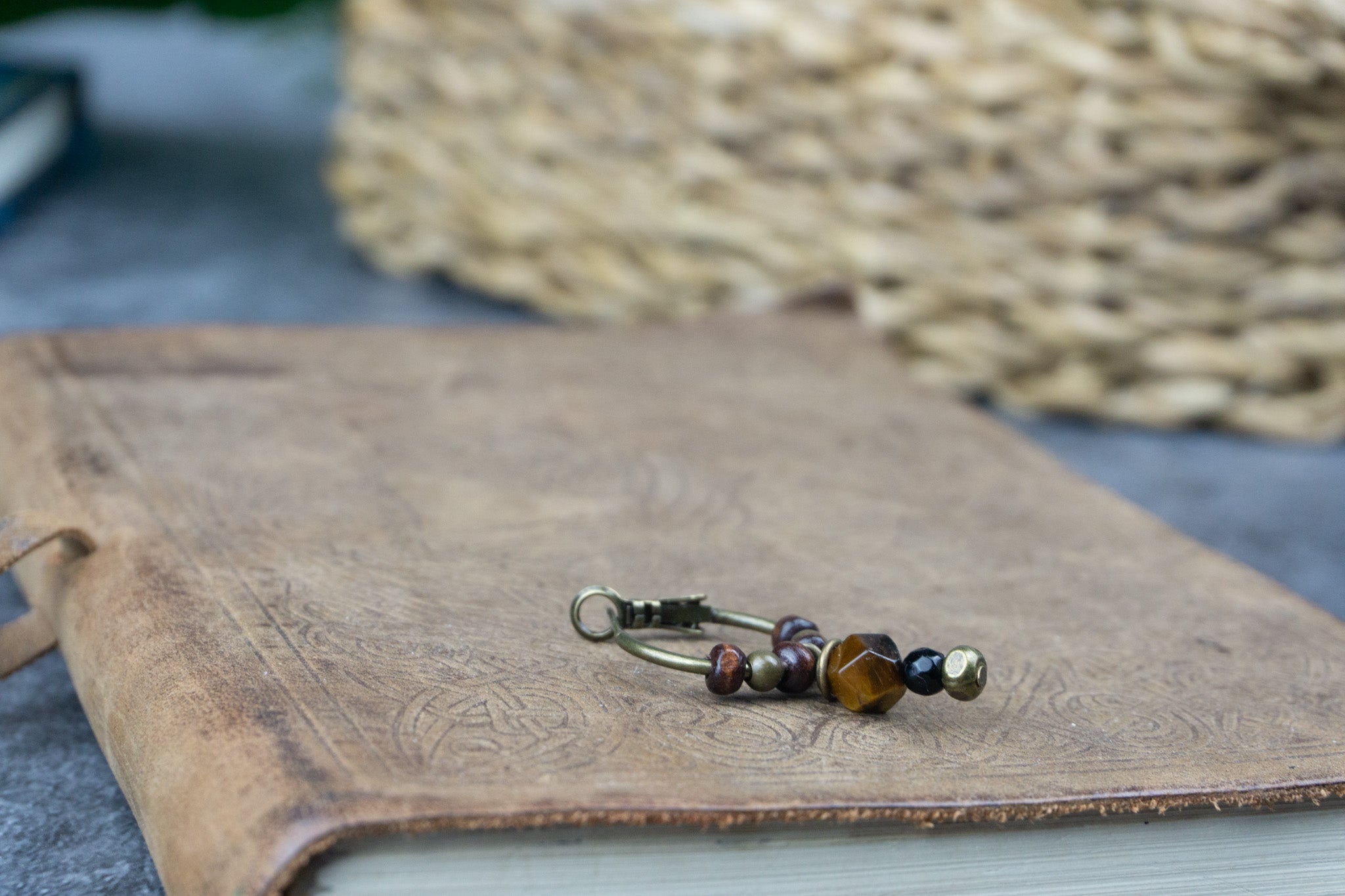 A bronze hoop earring, with wooden and brass beads, a dangling tiger eye and black onyx stone 
