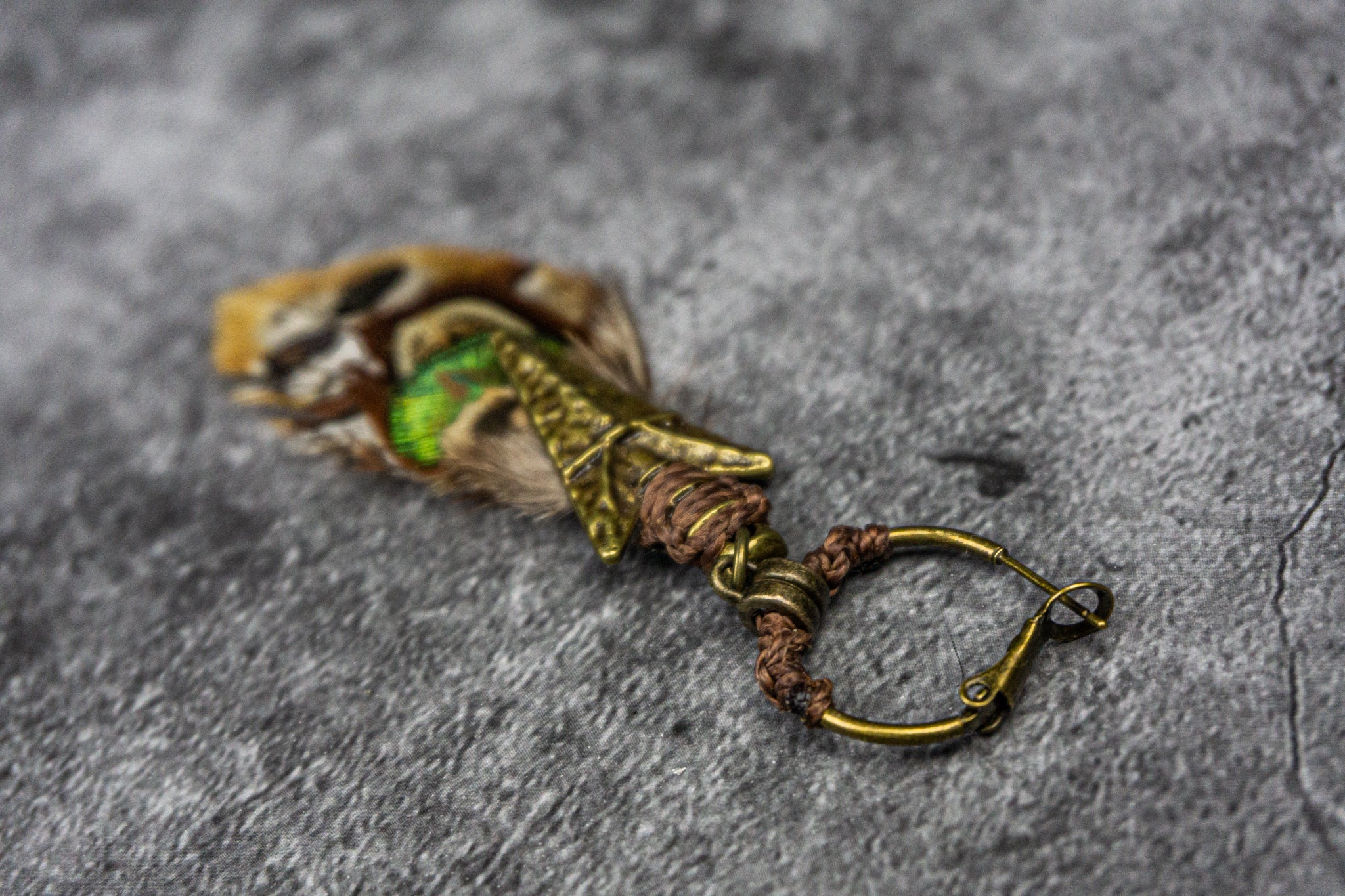 big brass hoop pirate earring with a tribal bronze arrow and an assemblage of different feathers in earthy shades- Wander Jewellery