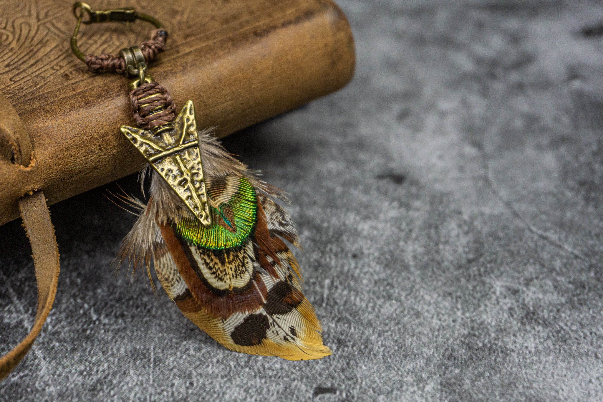 hoop earring with a tribal bronze arrow and an assemblage of different feathers in earthy shades- Wander Jewellery