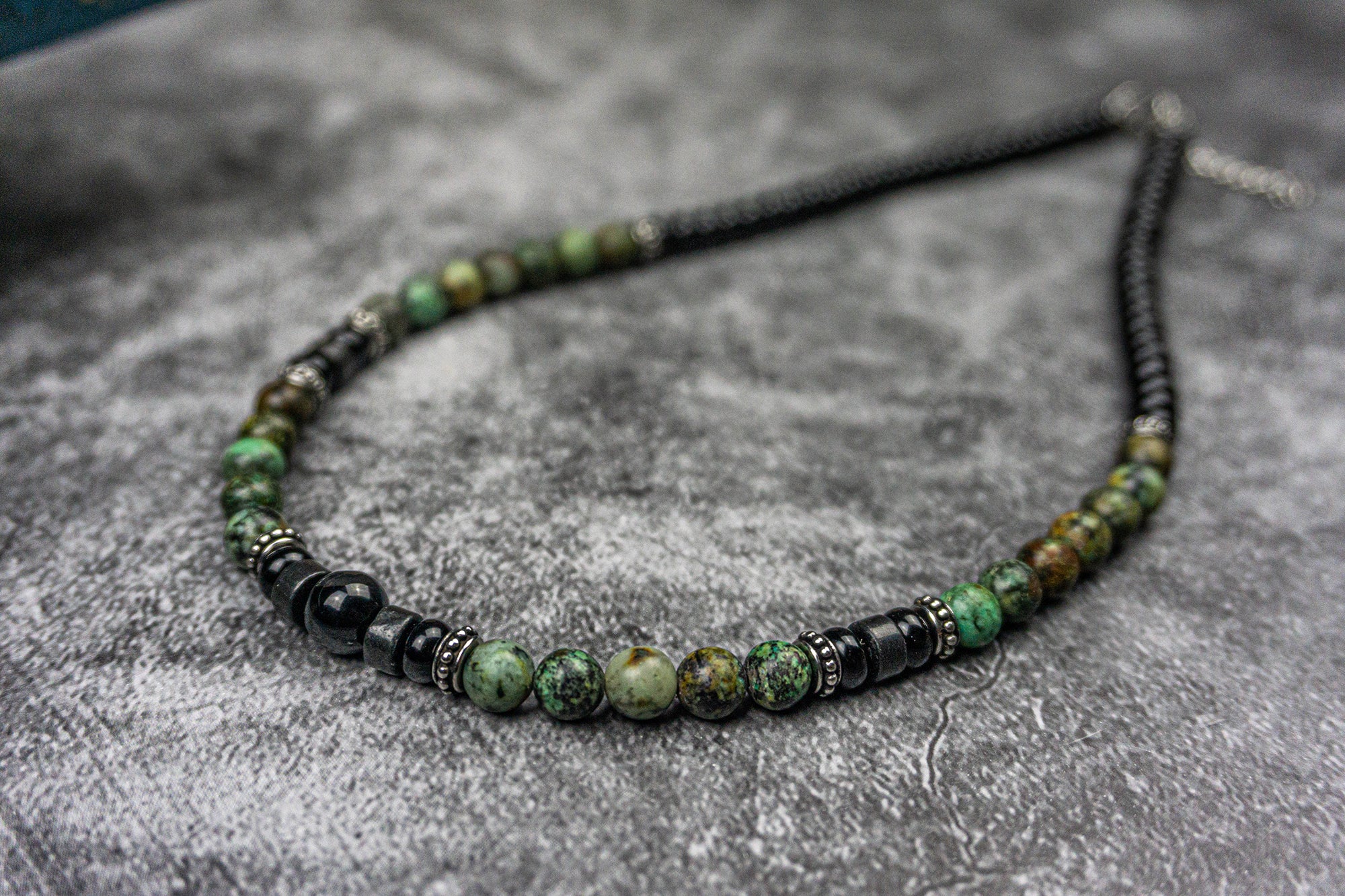 Close picture of a short necklace made of black onyx and green african turquoise gemstones, and stainless steel spacer beads