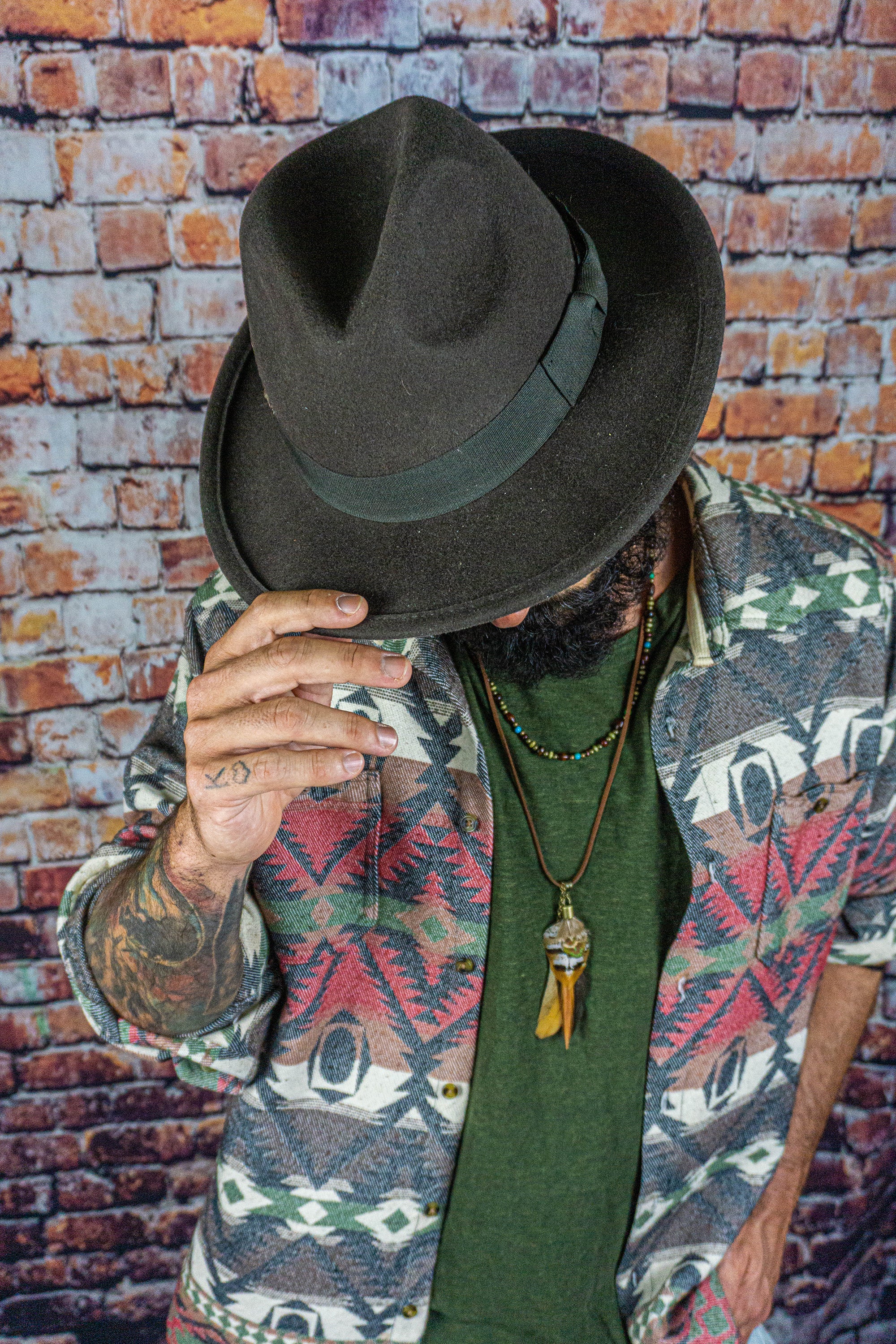 men wearing a hat and a boho  leather necklace set  with a feather as pendant