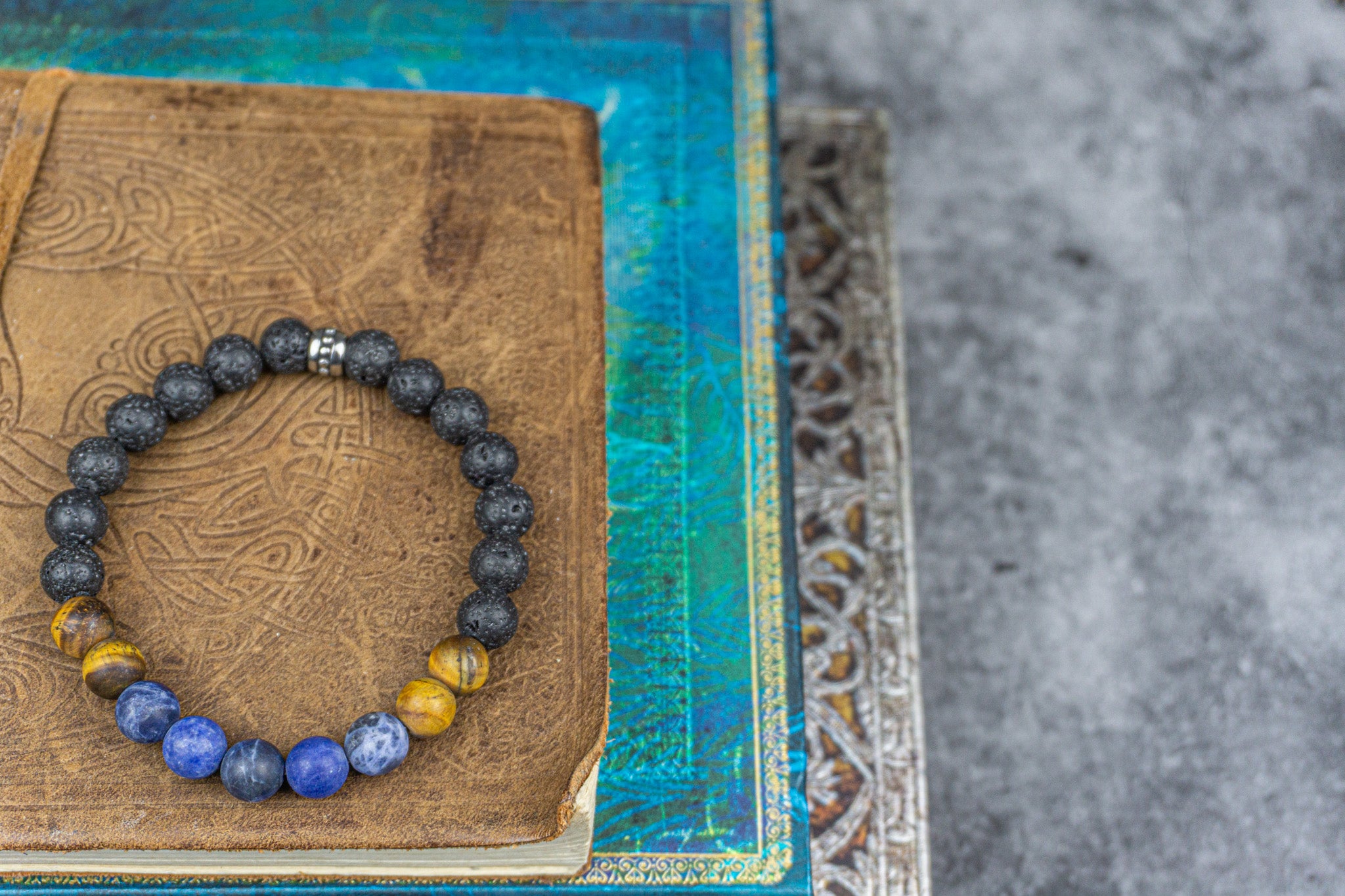 bracelet made of lava stone tiger eye sodalite, on a pile of books